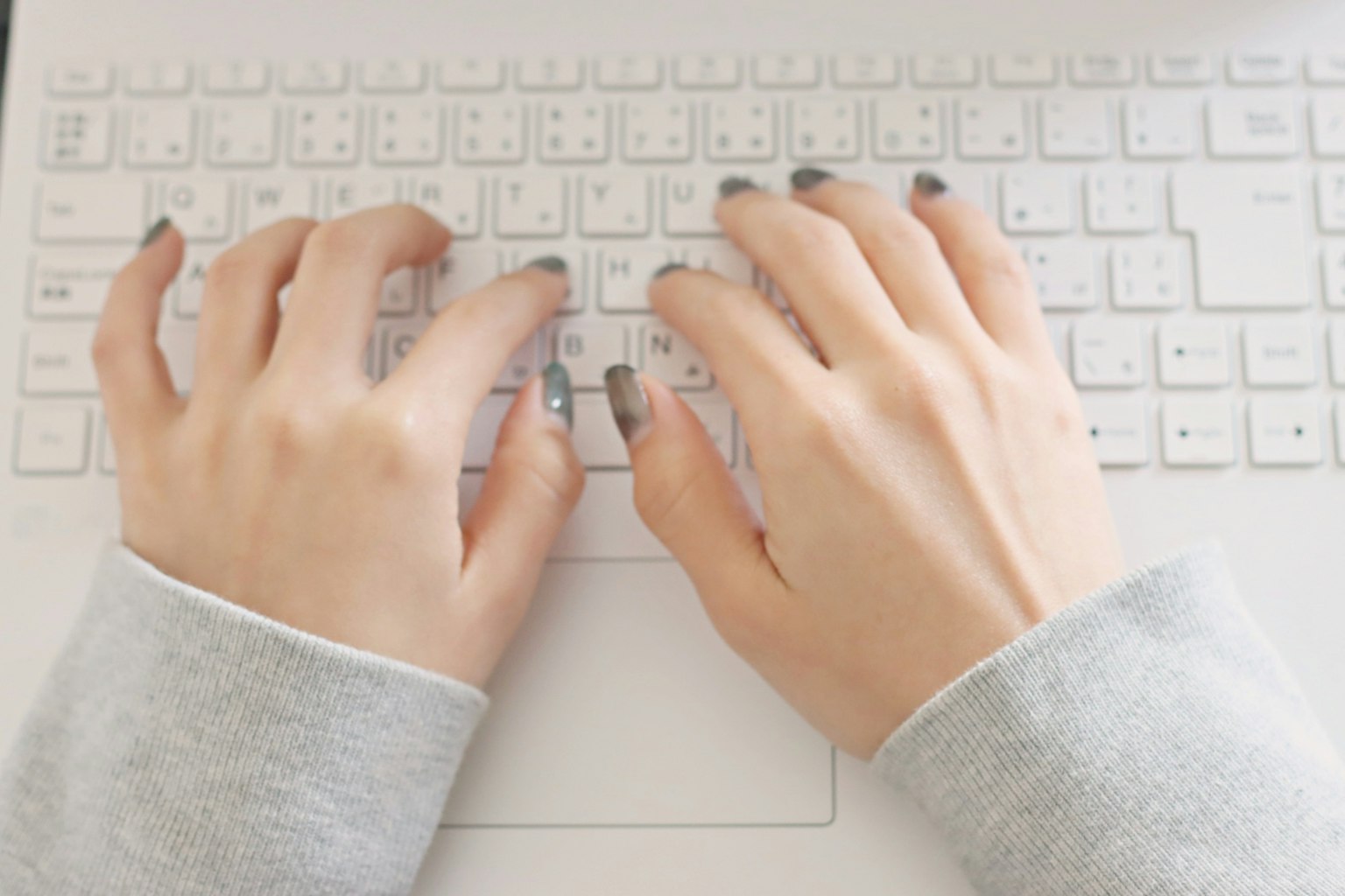 Manos escribiendo en un teclado blanco
