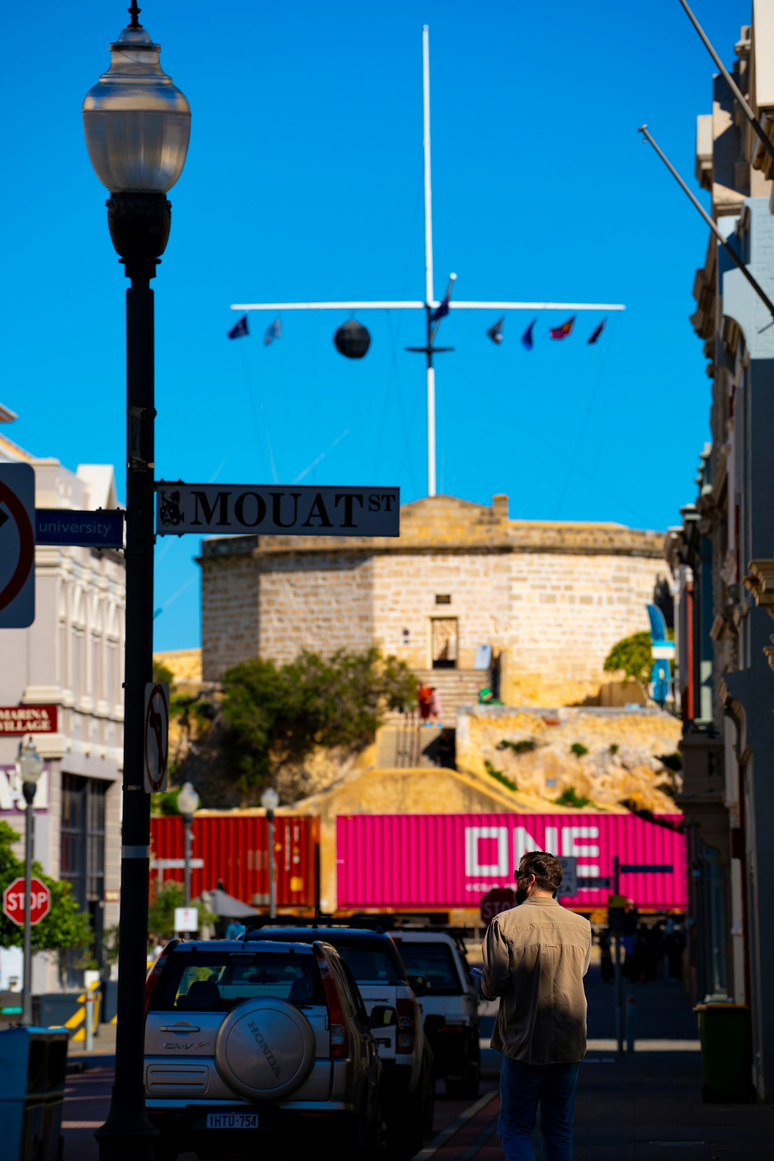 Vista di strada con un edificio storico sotto un cielo blu e container colorati