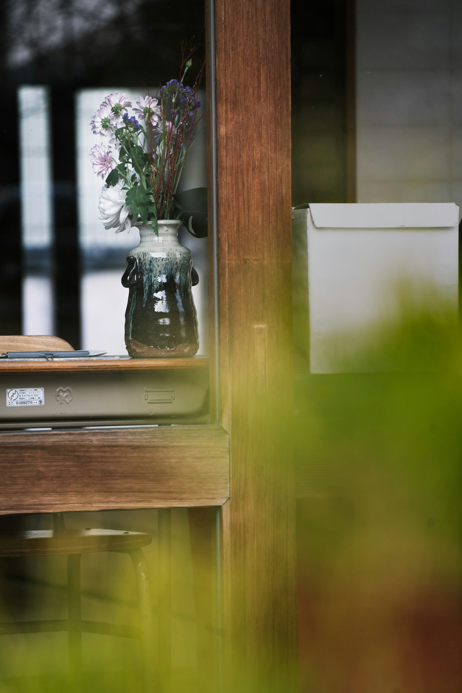 Un vaso di vetro con fiori su un davanzale di legno