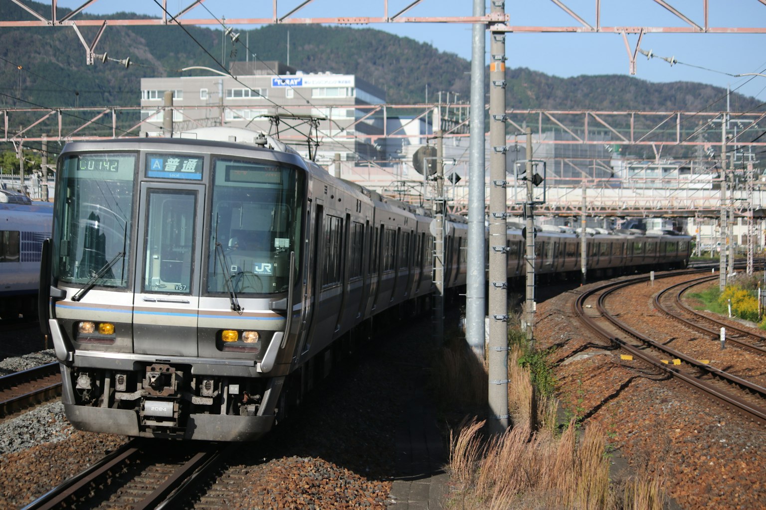 Ein japanischer Zug, der eine Kurve fährt, mit städtischen Gebäuden im Hintergrund