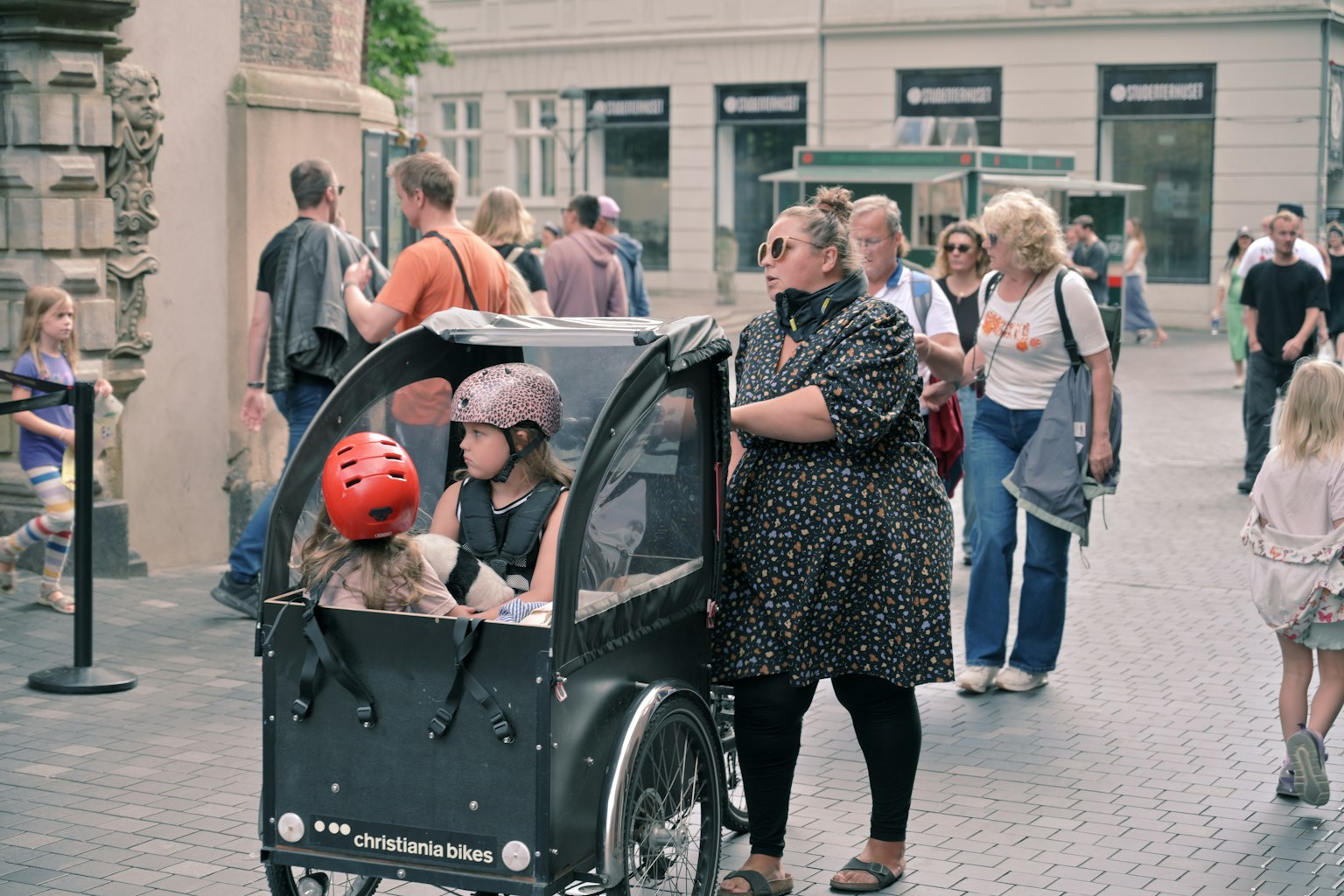 번화한 거리에서 자전거 트레일러에 있는 아이들과 그들의 어머니의 장면