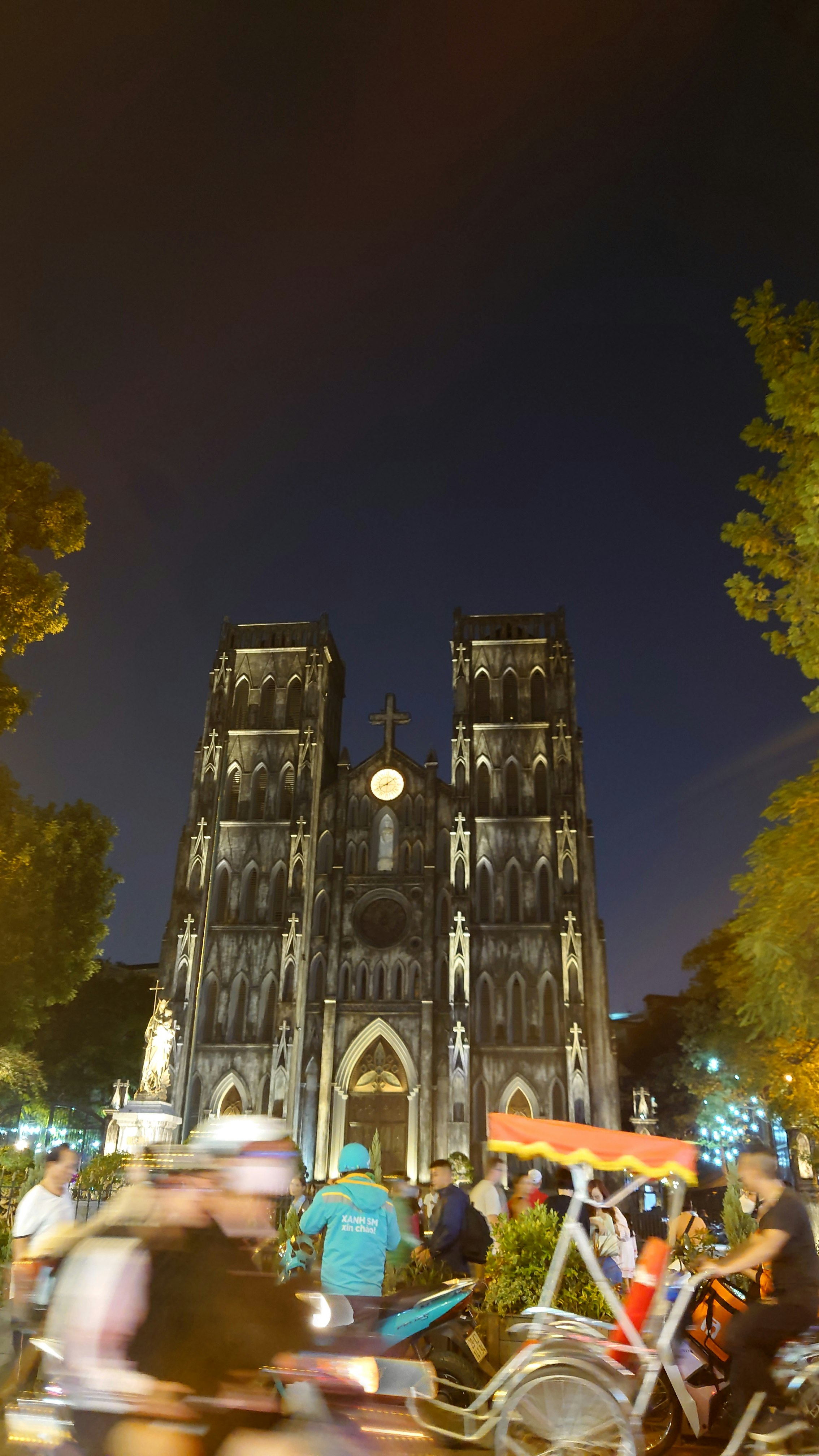 nächtlicher Platz vor einer Kathedrale mit Fahrrädern und Menschen