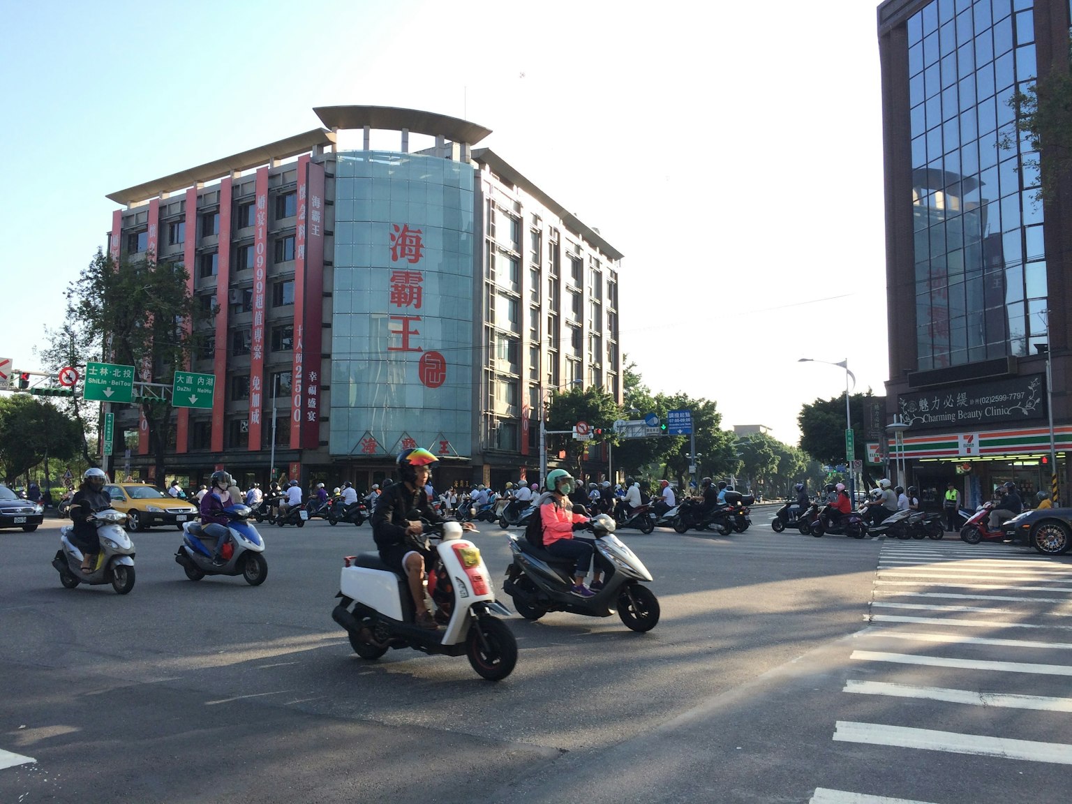 Ngã tư đông đúc với nhiều xe máy và xe tay ga gần các tòa nhà hiện đại
