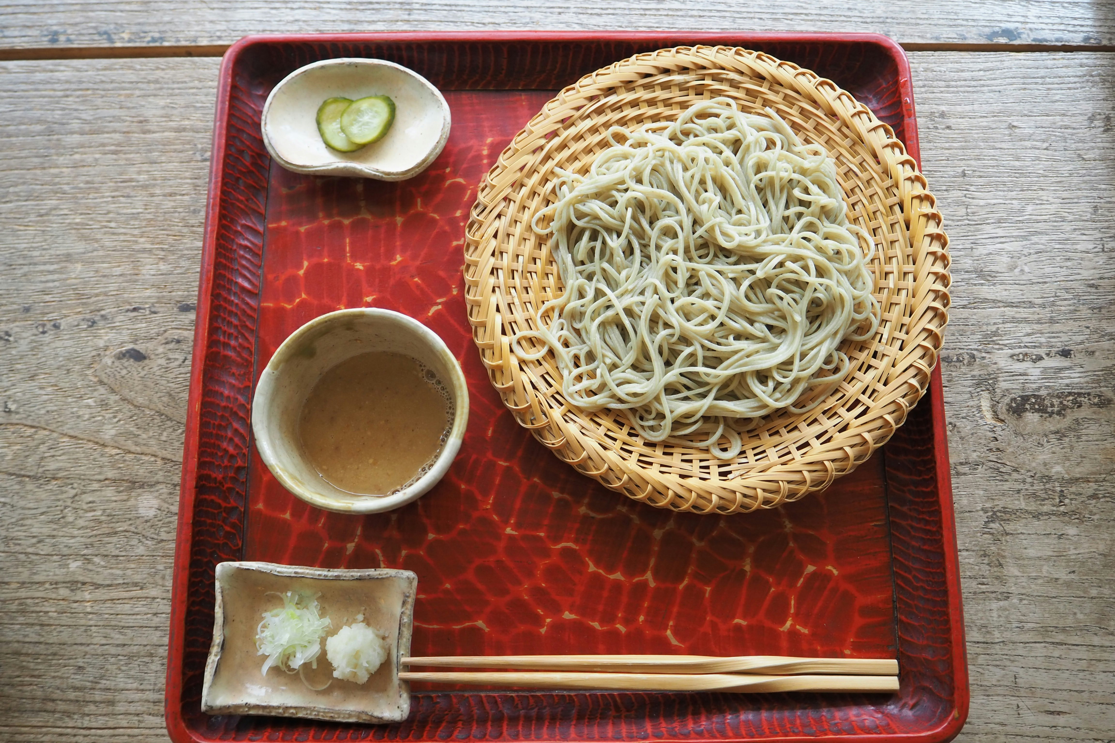 Fideos soba y condimentos sobre una bandeja lacada roja