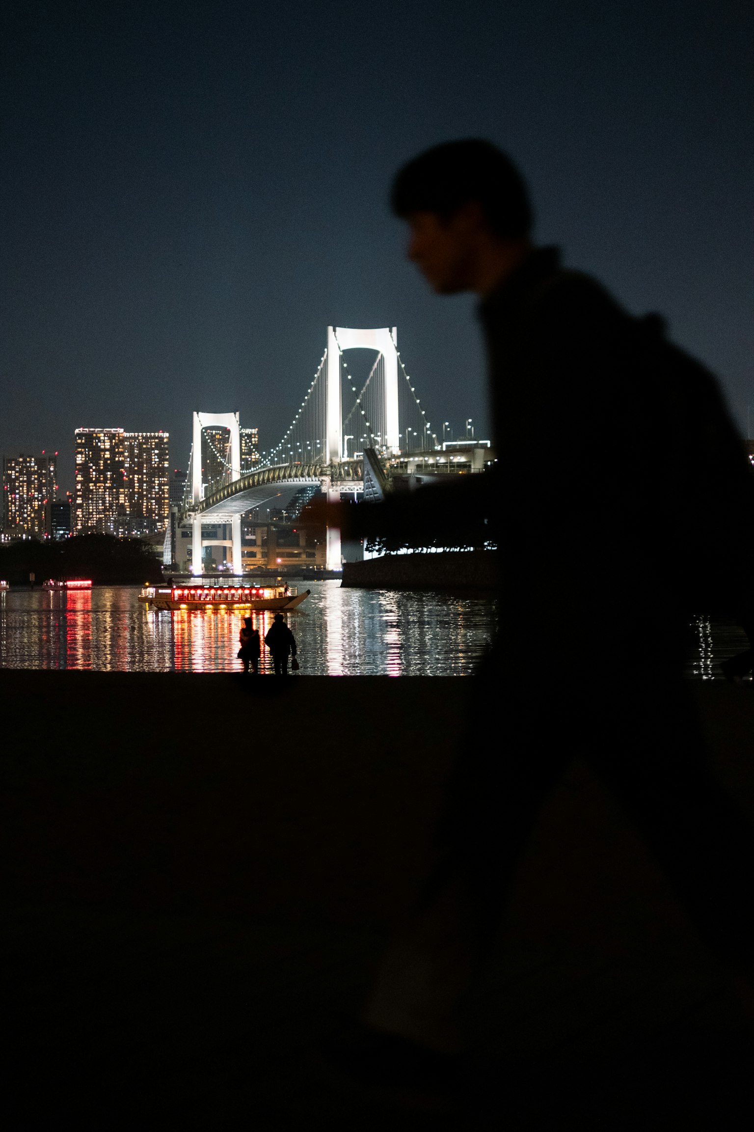 Silhouette d'une personne marchant avec le pont Rainbow la nuit