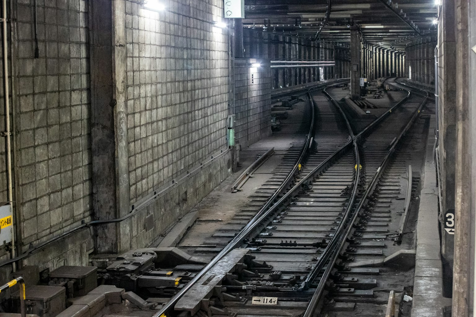 Binari curvi in un tunnel della metropolitana sotterranea con muri in blocchi di cemento