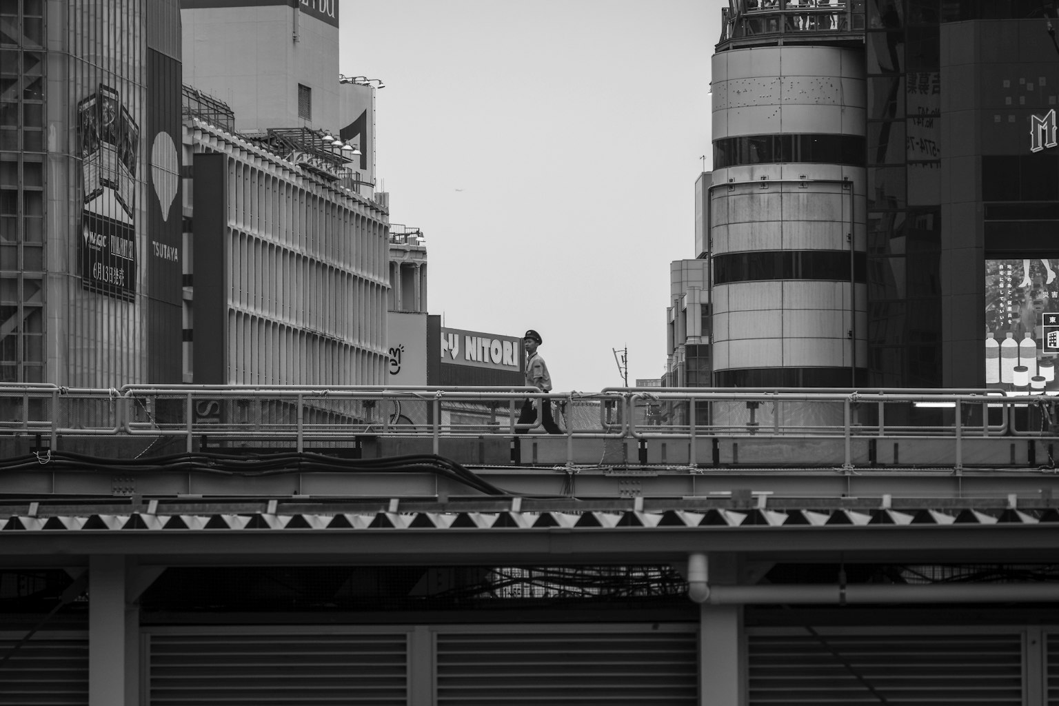 黑白城市景觀，展示一個人站在步道上，周圍是摩天大樓和廣告