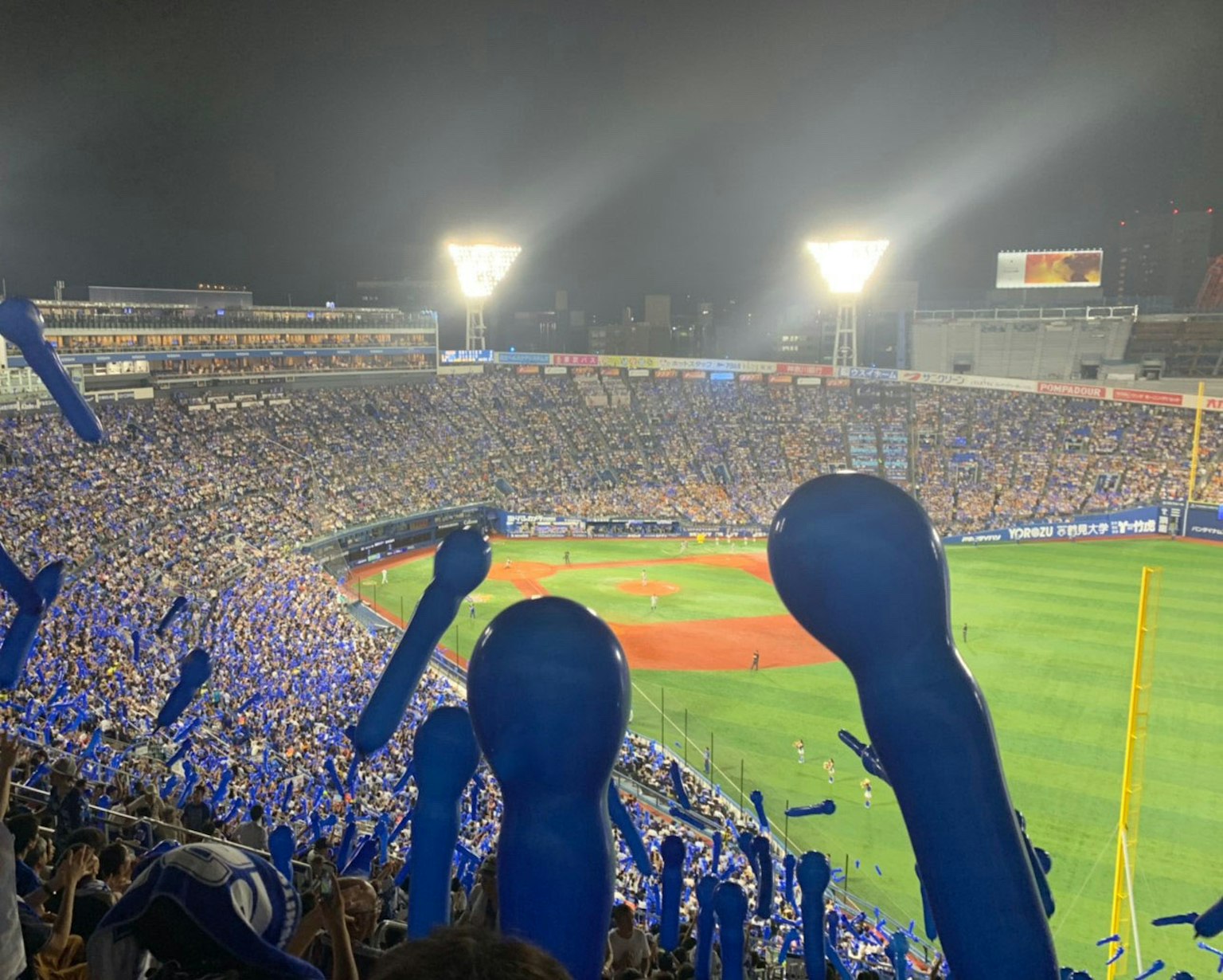 Scena notturna di uno stadio di baseball con fan che tengono oggetti di sostegno blu