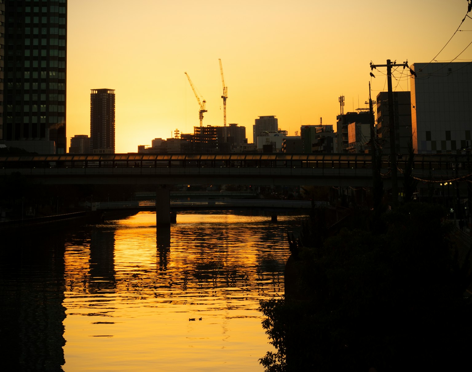Silhouette d'une ville au coucher du soleil avec des reflets sur l'eau