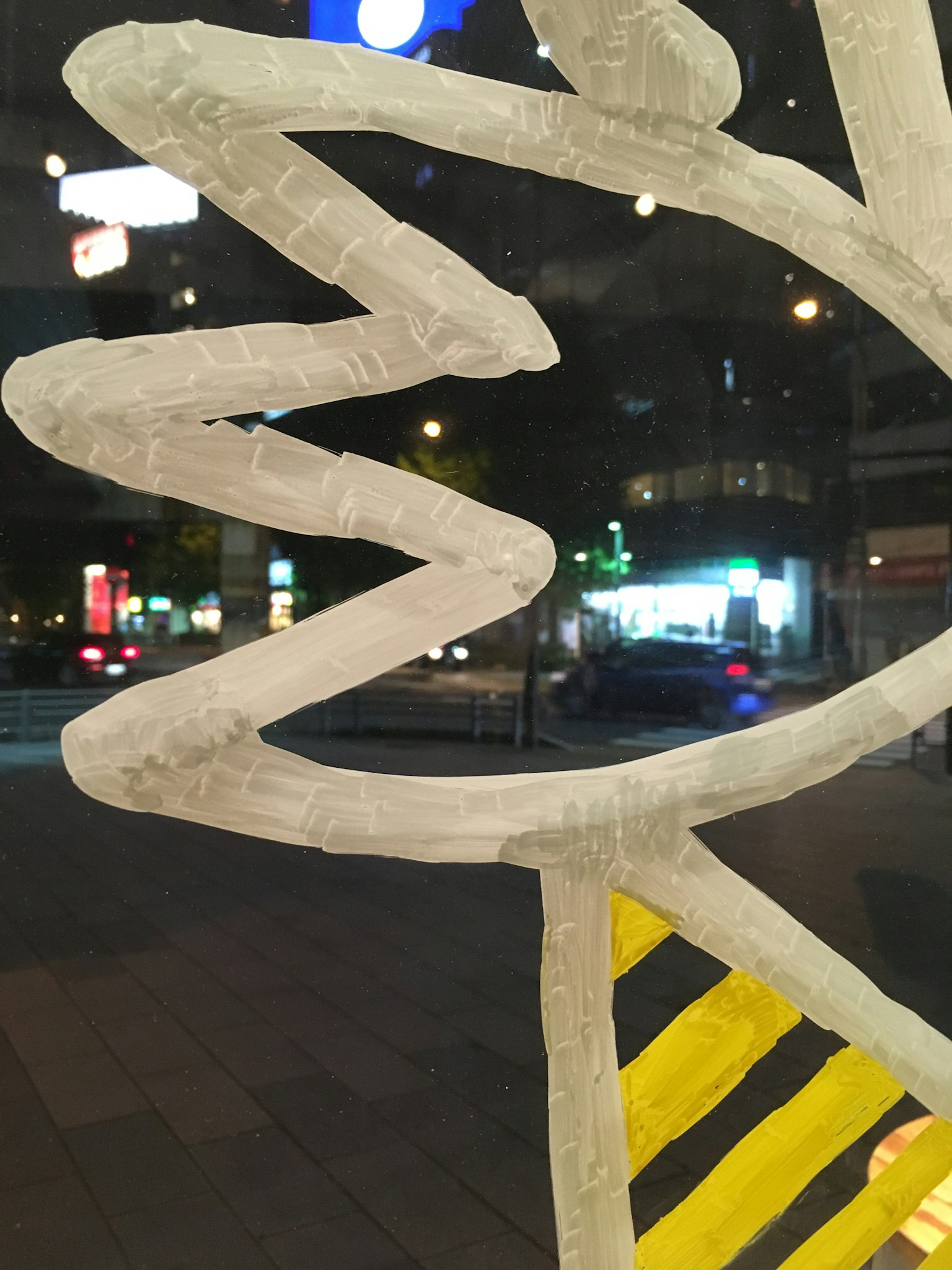 Abstraktes weißes Design mit gelben Streifen, gesehen durch ein Fenster einer nächtlichen Stadt