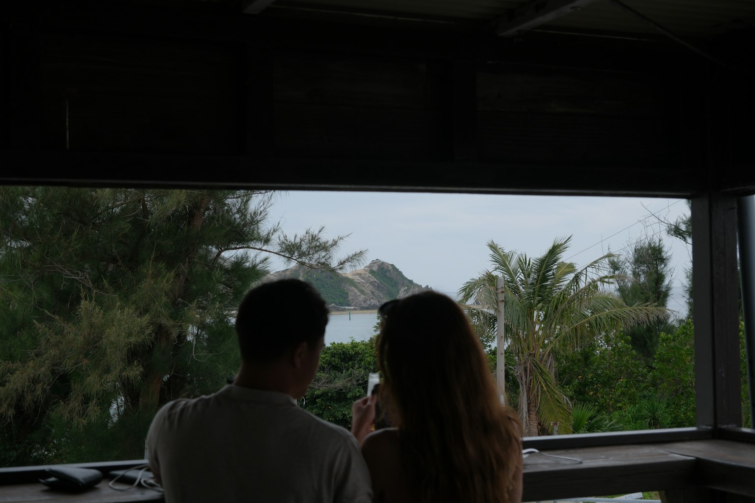 Silhouette eines Paares, das aus einem Fenster mit Grün und Meerblick schaut