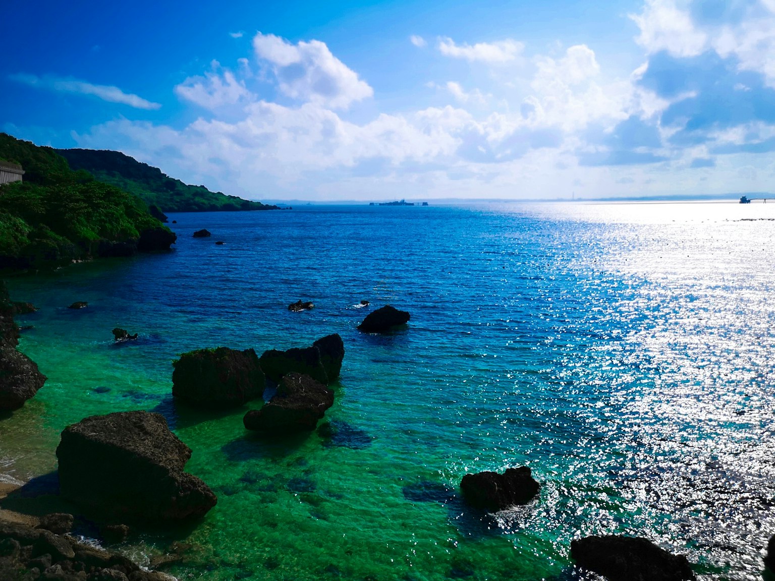 Hermoso paisaje de mar y cielo azules con rocas y costa verde