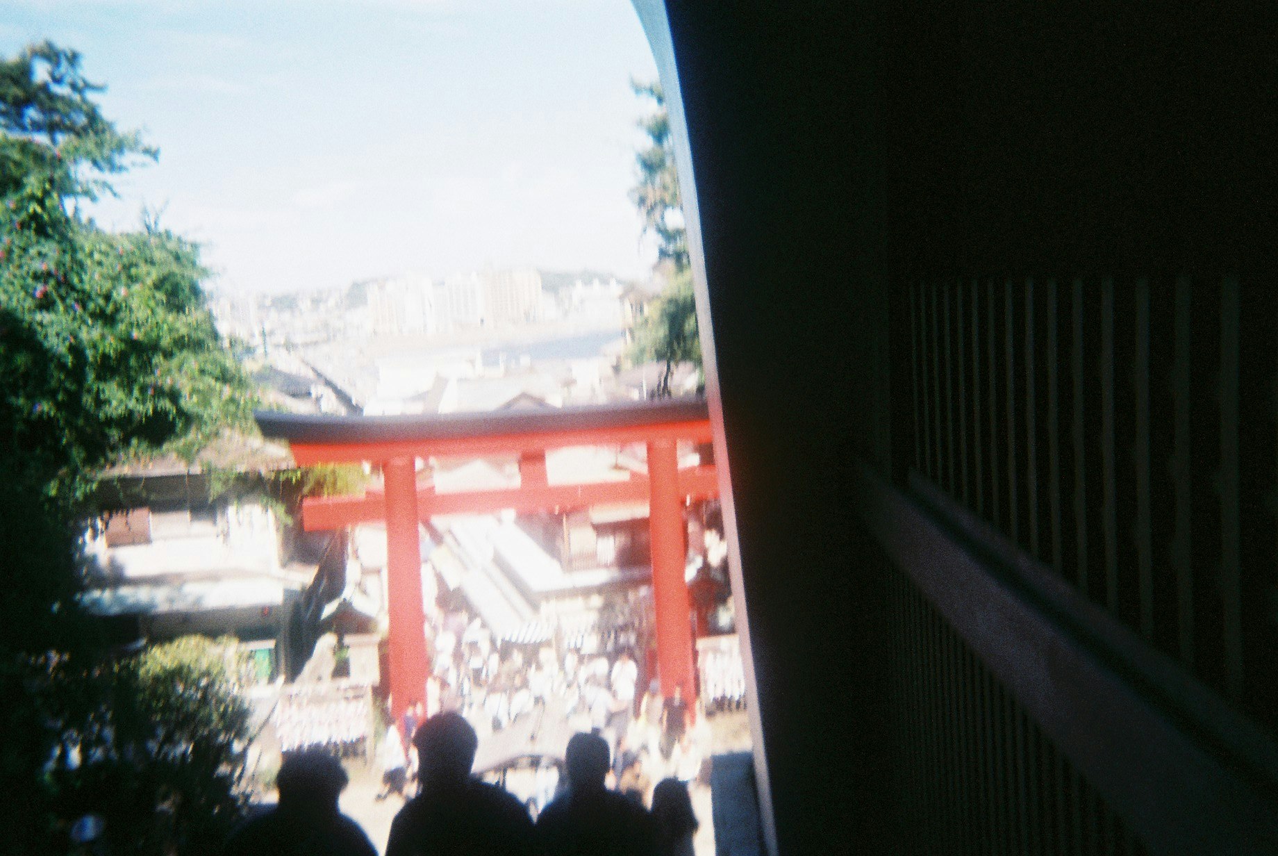 鳥居のある神社の参道を人々が行き交う景色