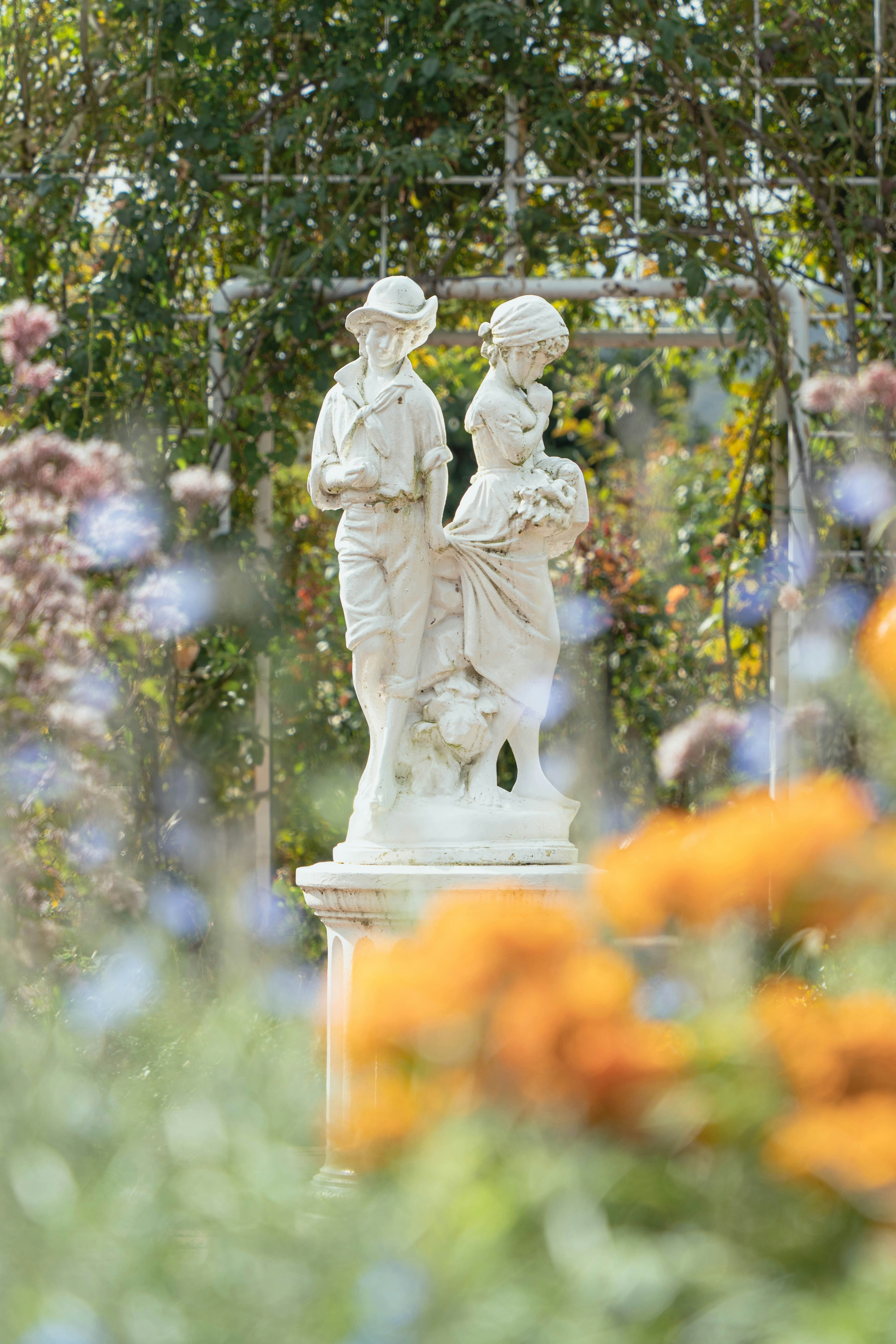 sculpted human figures standing among a flower garden