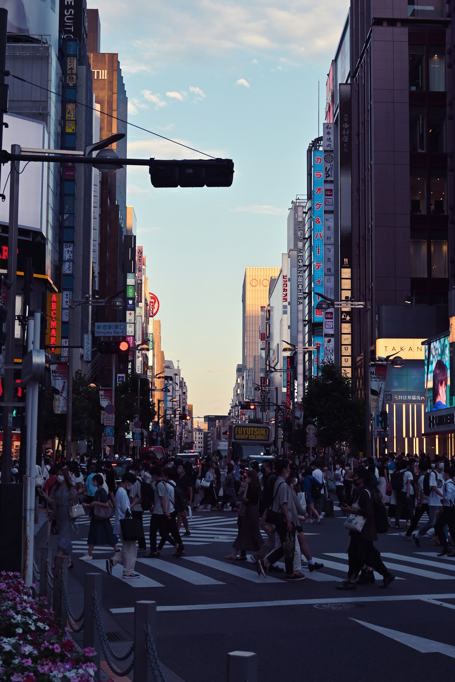 繁忙街道場景，人們穿越十字路口，周圍是建築和廣告