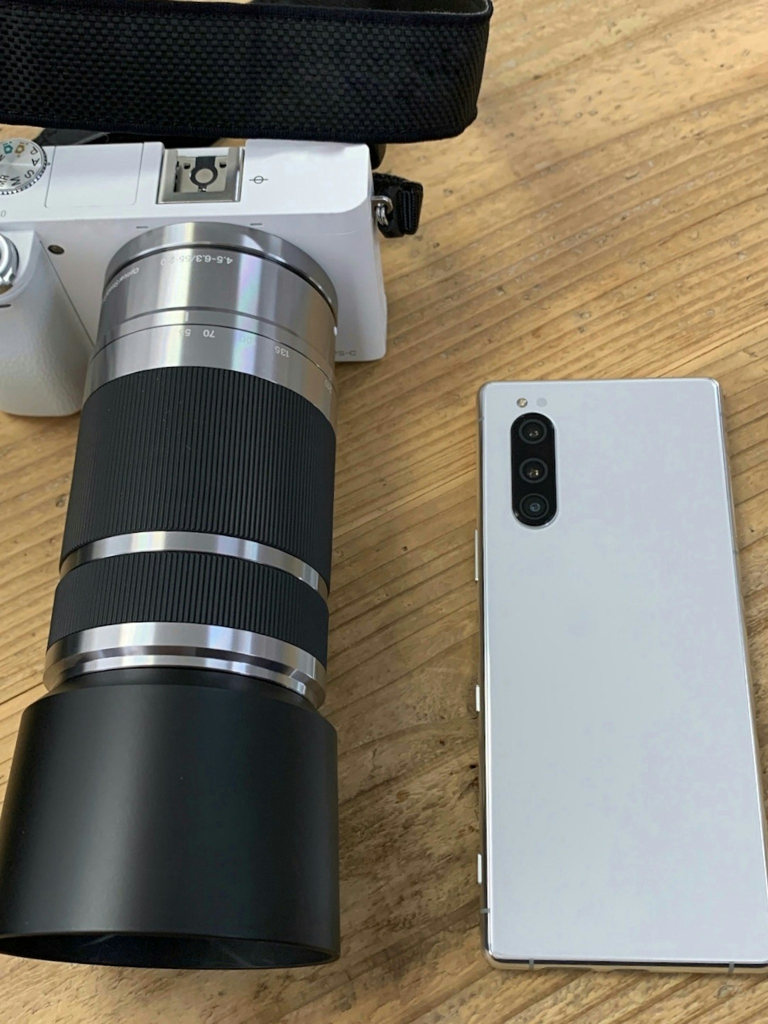 Kamera und Smartphone auf einem Holztisch platziert