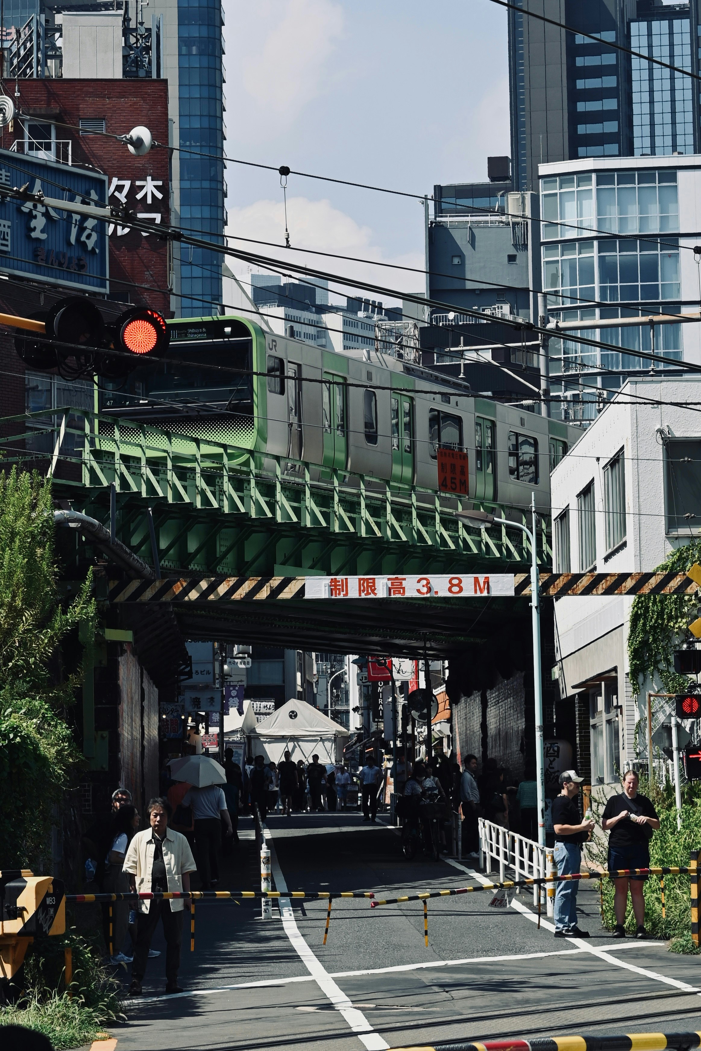 高架下を行き交う人々と電車のある都市の通りの風景