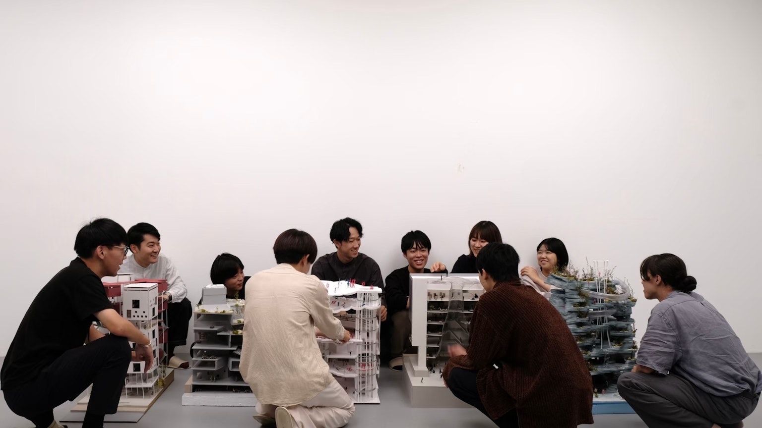一群人坐在桌子周圍，在藝術工作坊中檢查模型