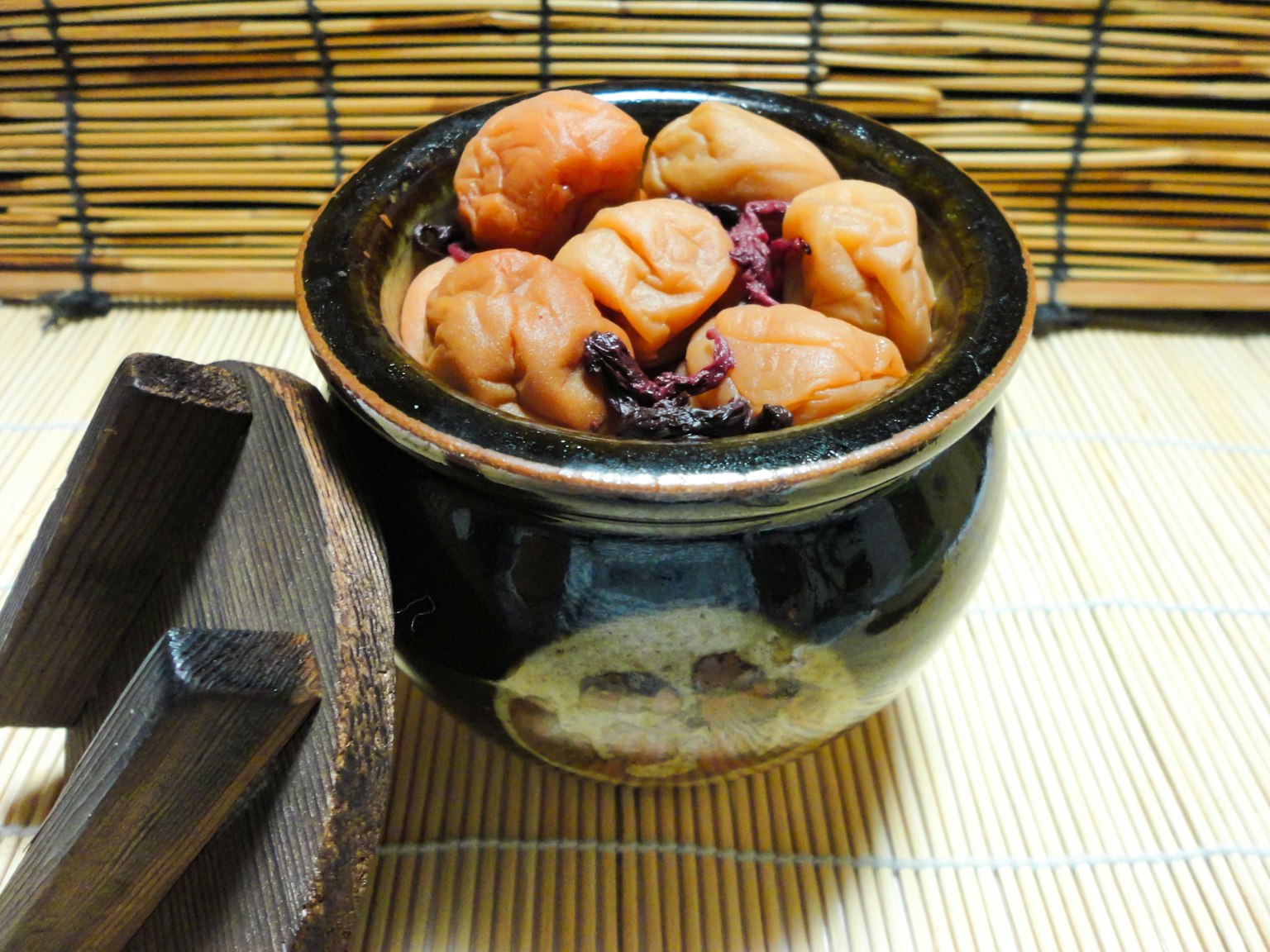 Sebuah guci keramik hitam yang diisi dengan plum umeboshi yang diasinkan