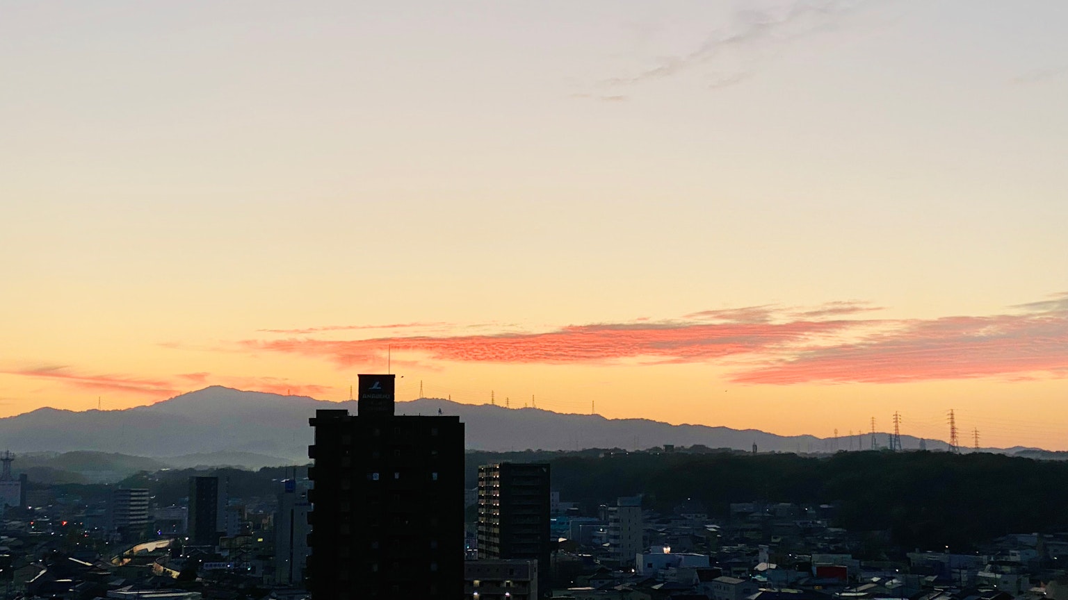 Stadtansicht mit Silhouetten von Bergen und einem Sonnenuntergangshimmel