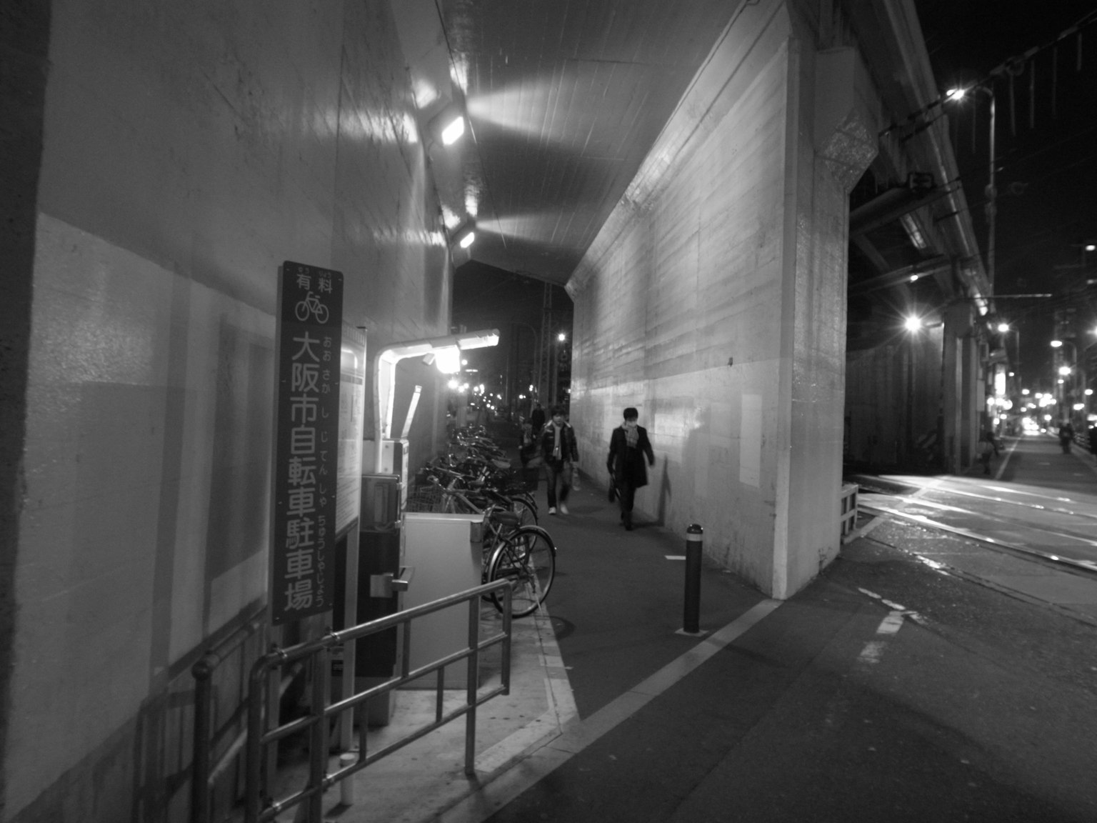 Image of a dark street with people walking on the sidewalk at night