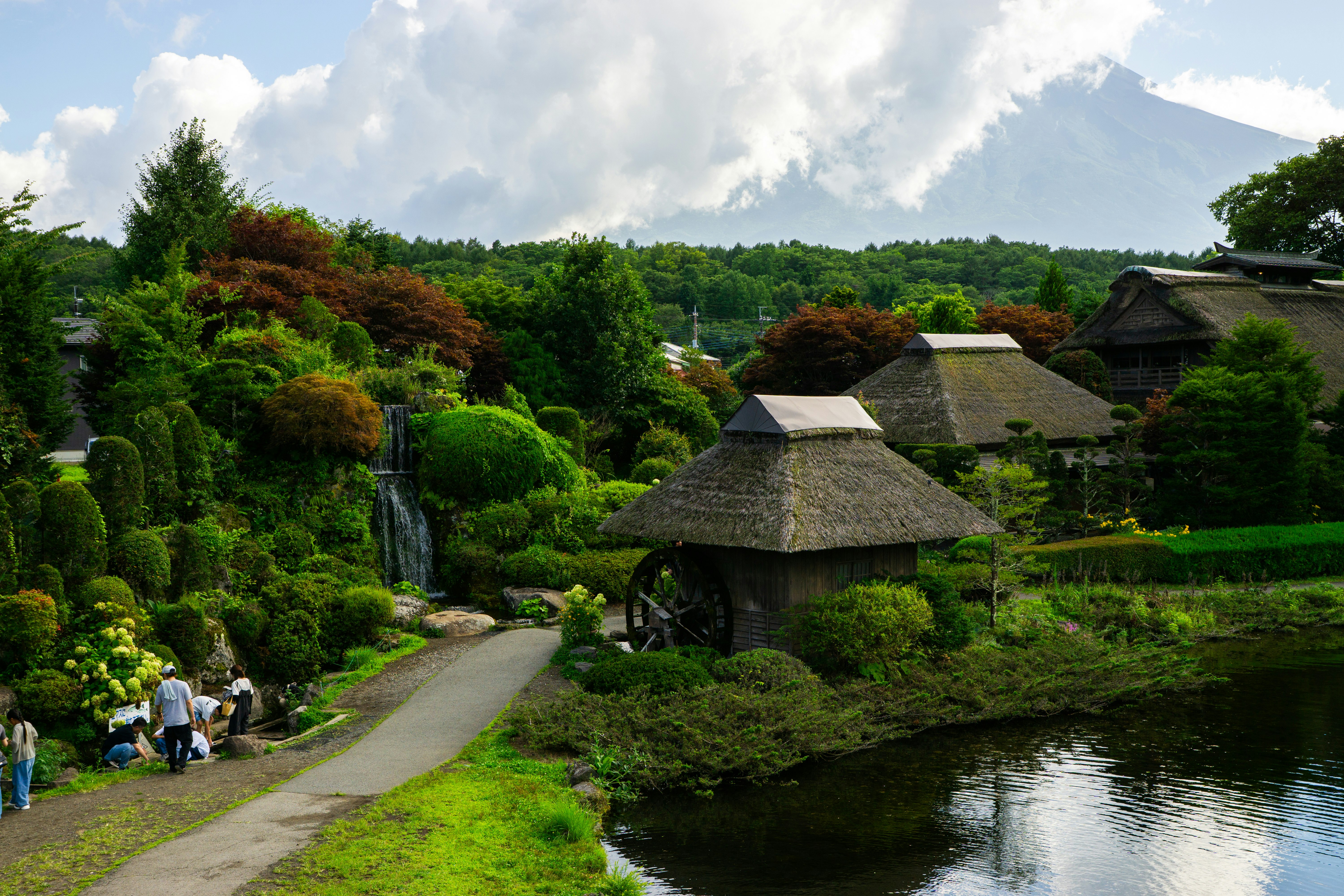 池塘旁的花園小徑與長滿青苔的石砌、茅草屋頂建築