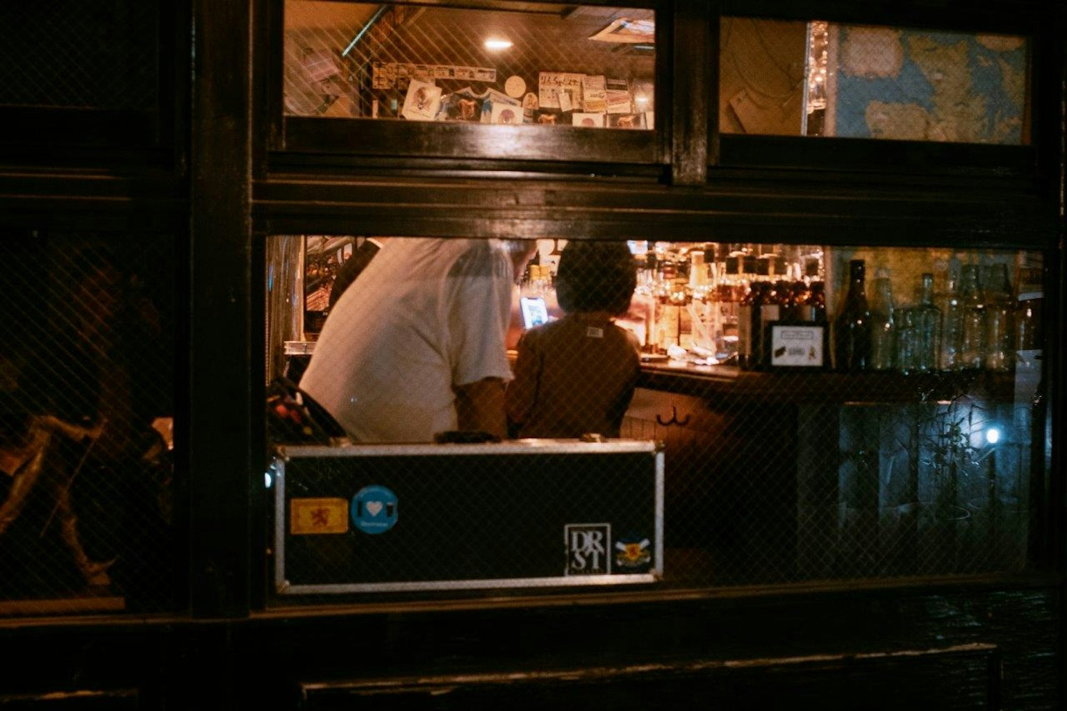 Persone che gustano drink in un bar con scaffali di bottiglie