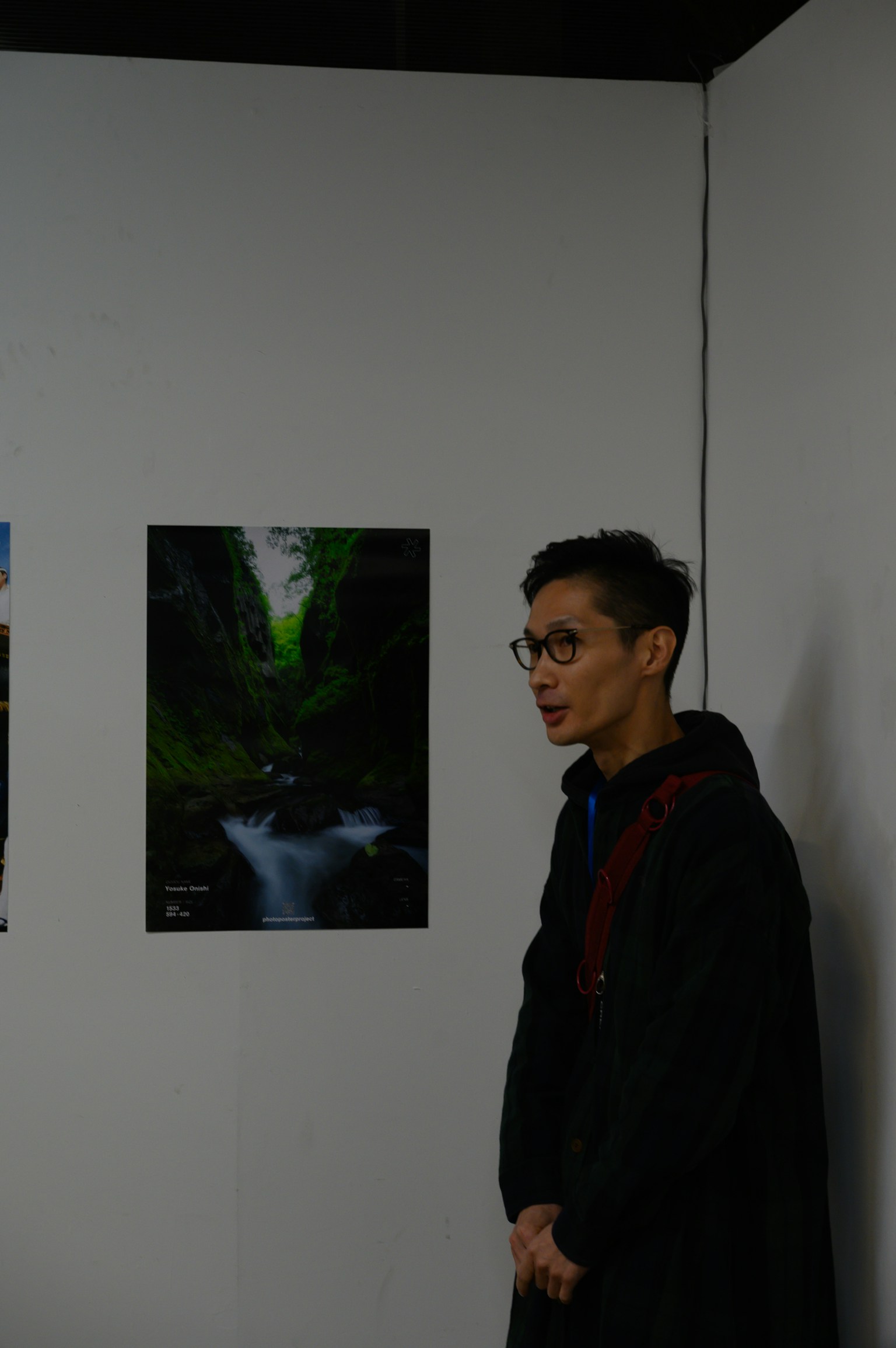 A man standing in front of a landscape photograph at an exhibition