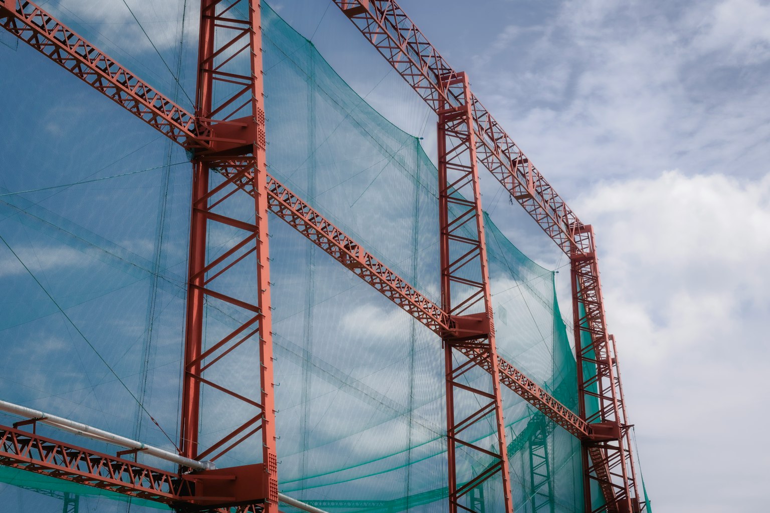 Construction site structure covered with blue netting and red steel frame