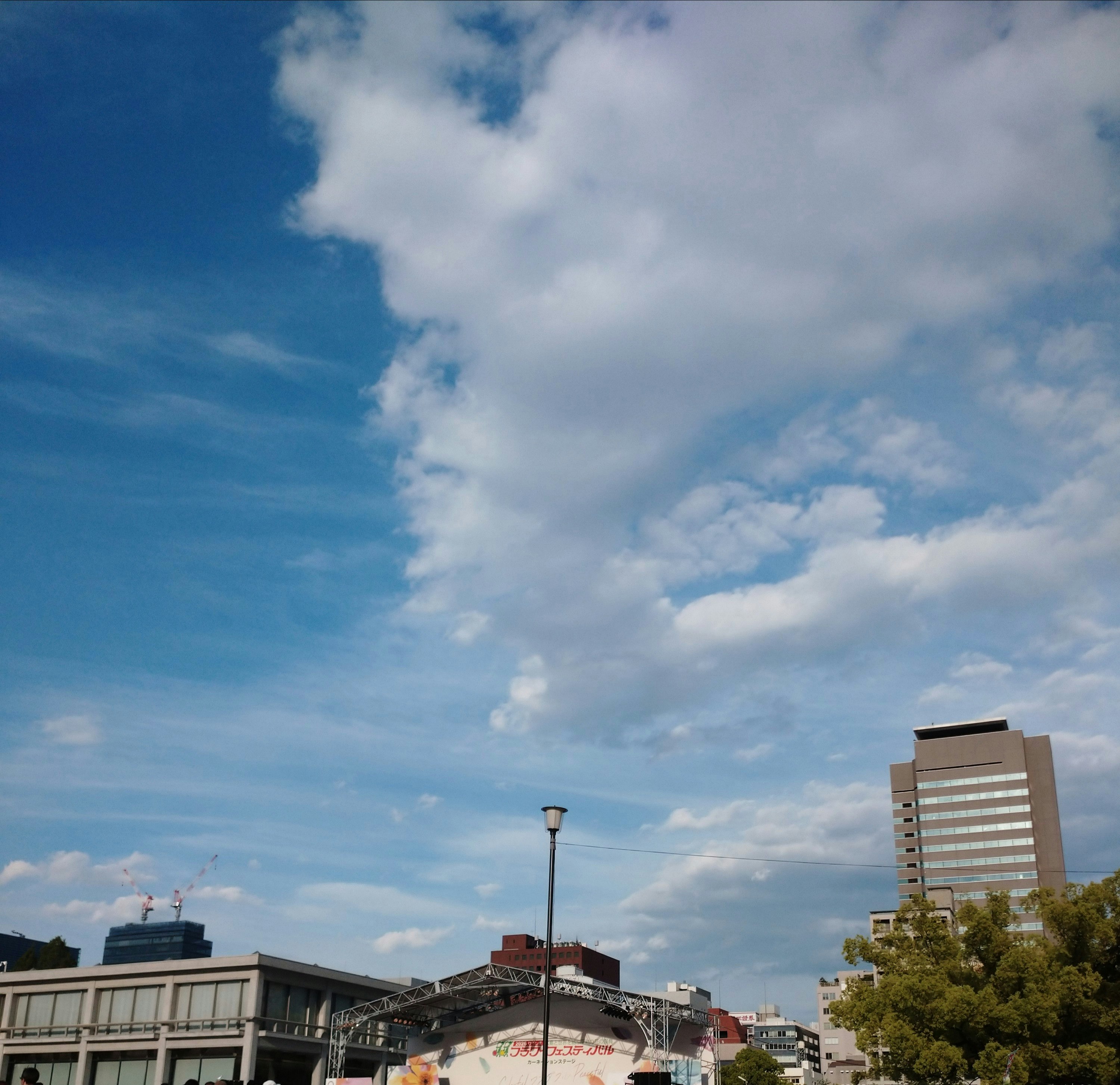青空の下で高層ビルと駅前の広場が見える都市風景