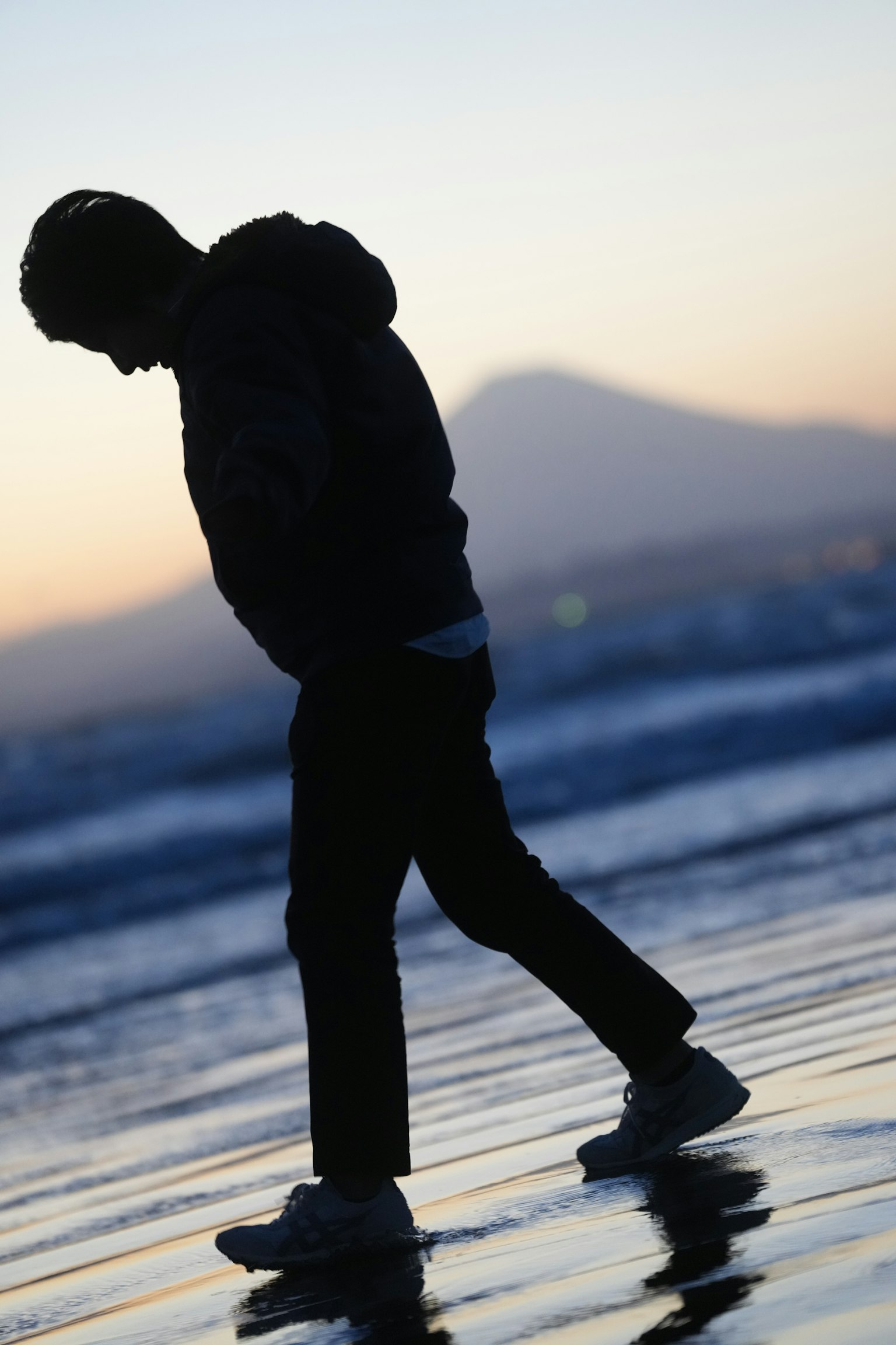 Silhouette of a man walking on the beach at sunset