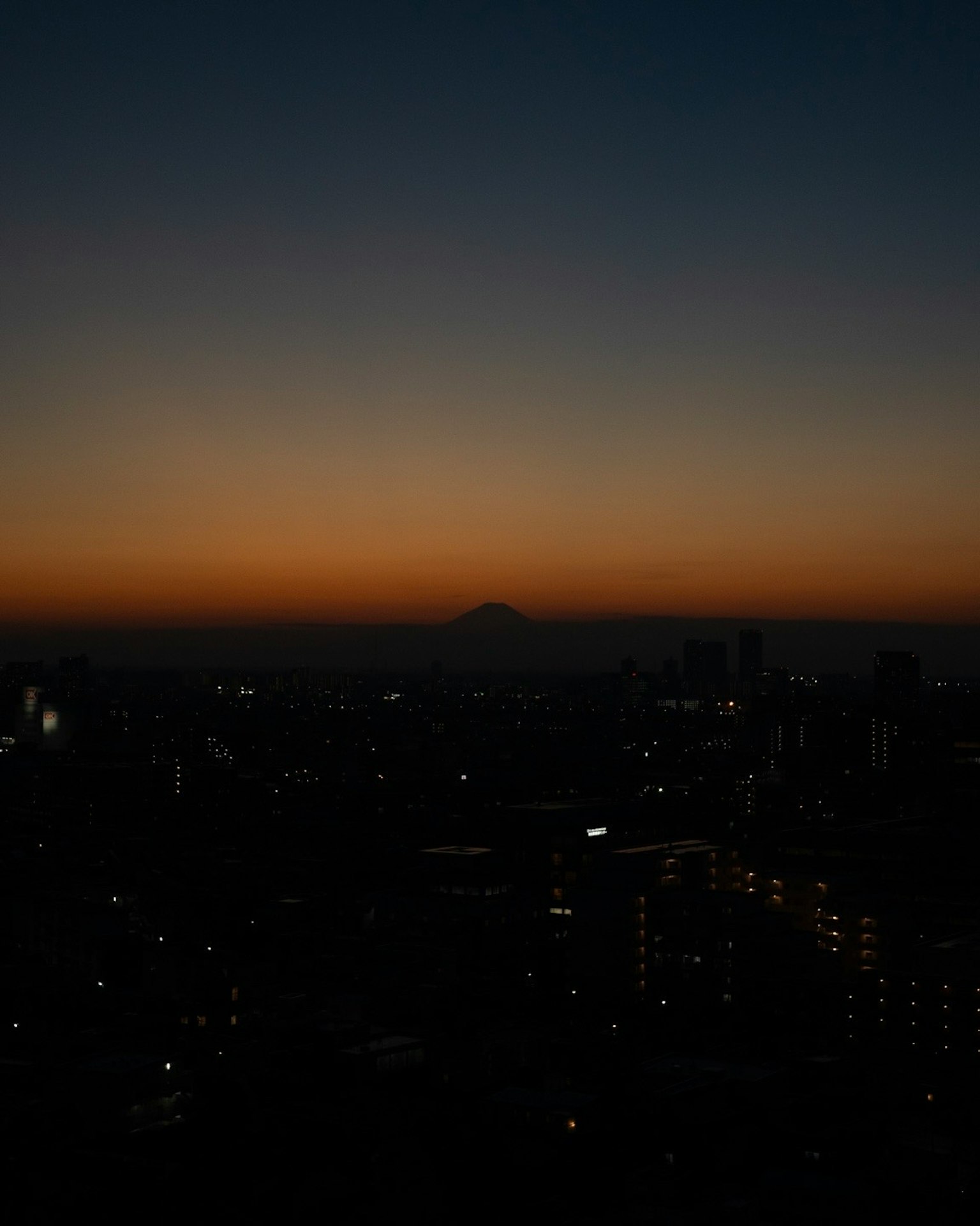 東京の夜景と富士山のシルエットが見える夕暮れの風景