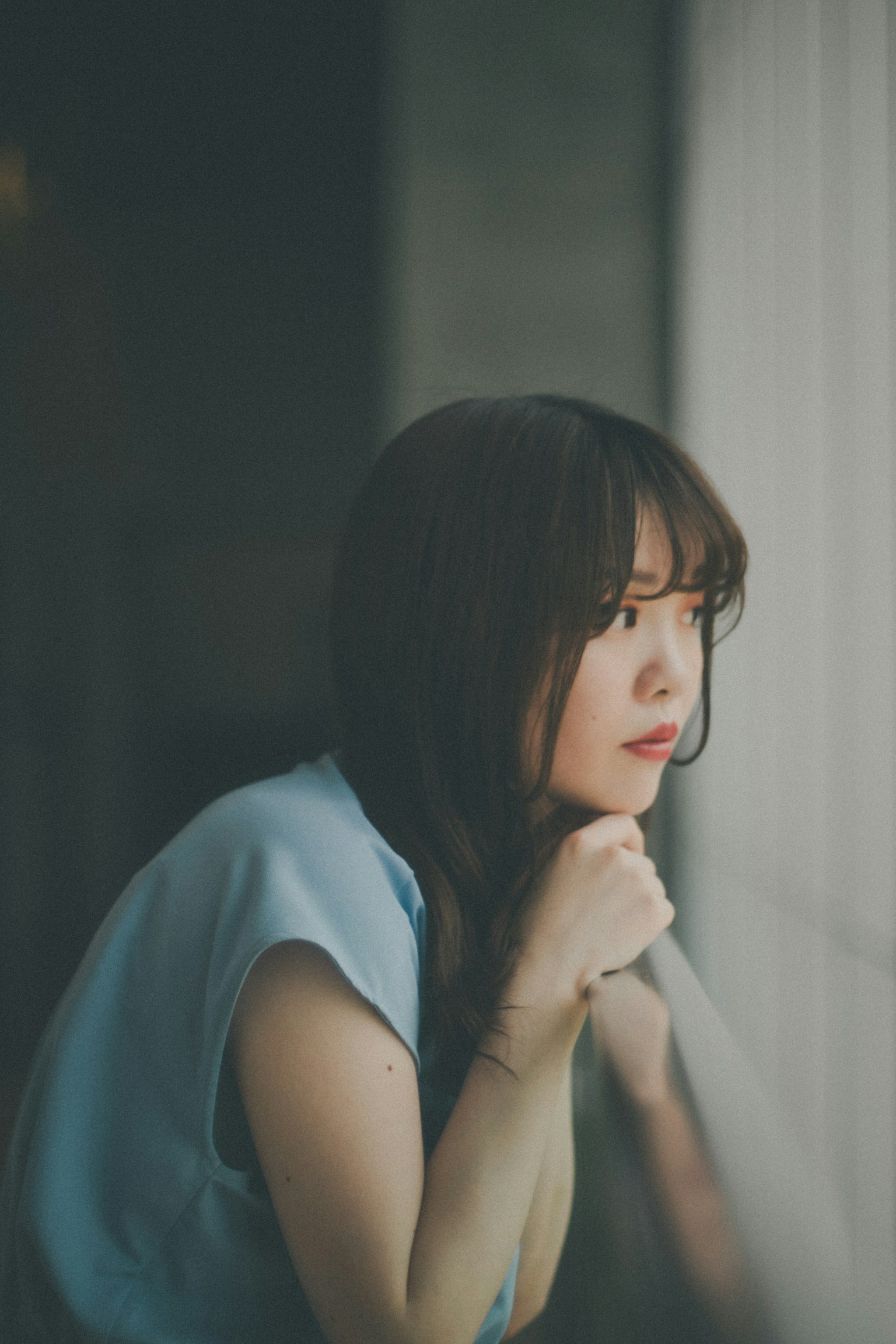 A woman gazing out the window with soft light and shadow contrast