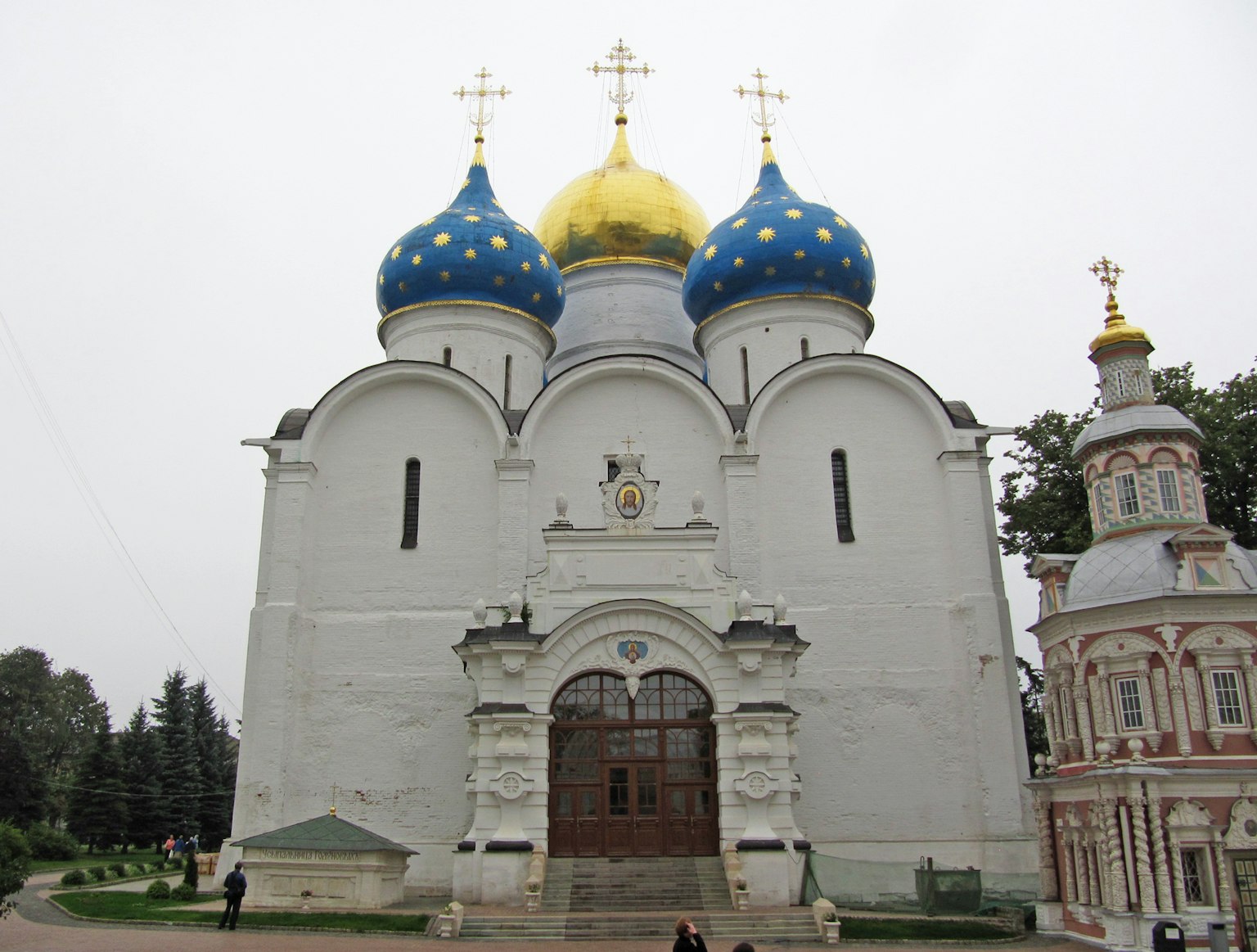 Exterior of a white church with blue and golden domes