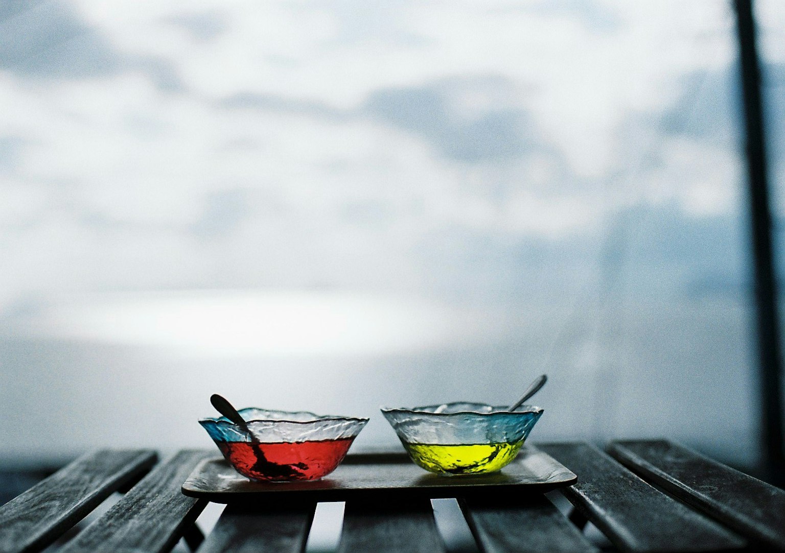 Two bowls of red and yellow jelly placed on a wooden table