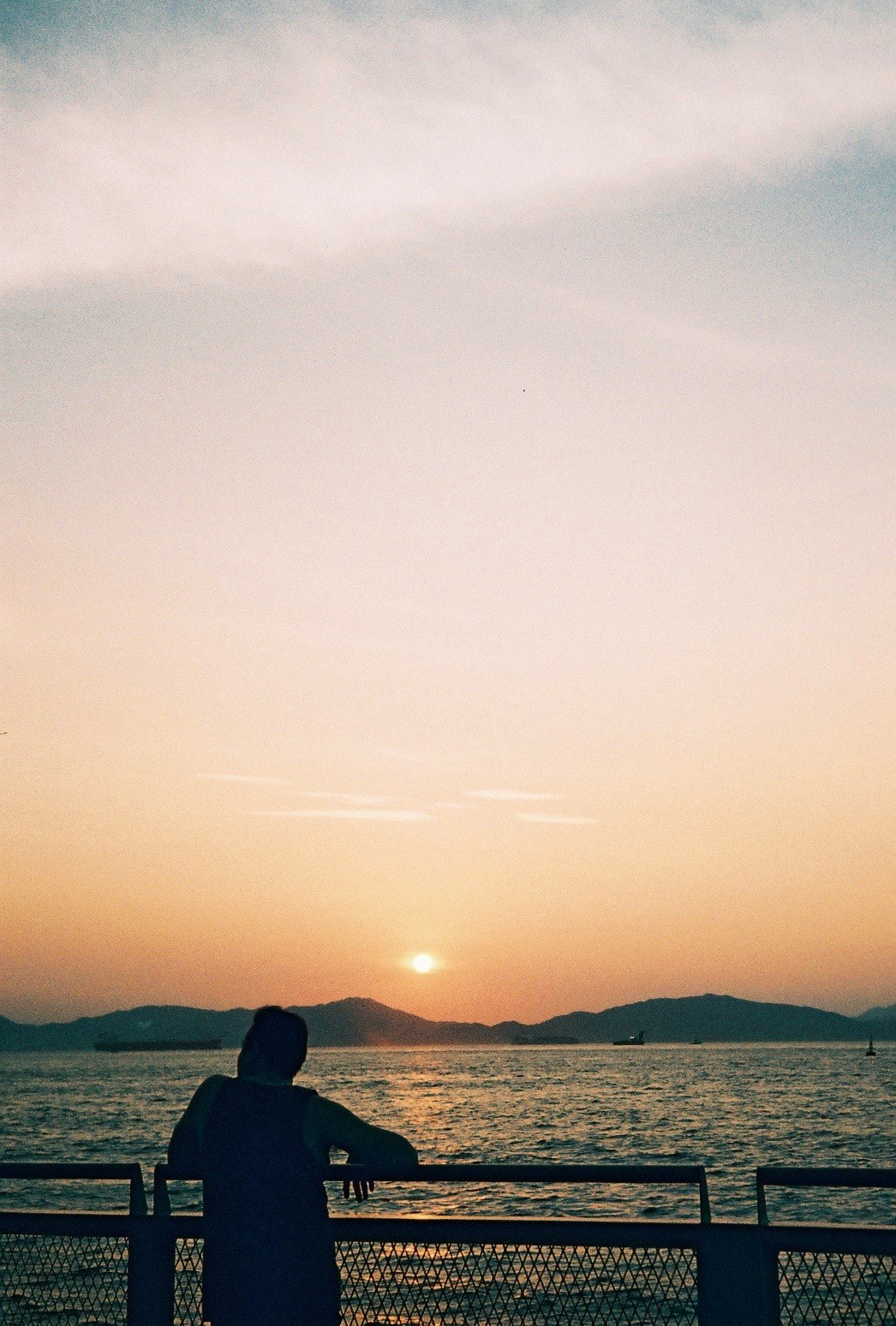夕暮れの海を見つめる人の後ろ姿