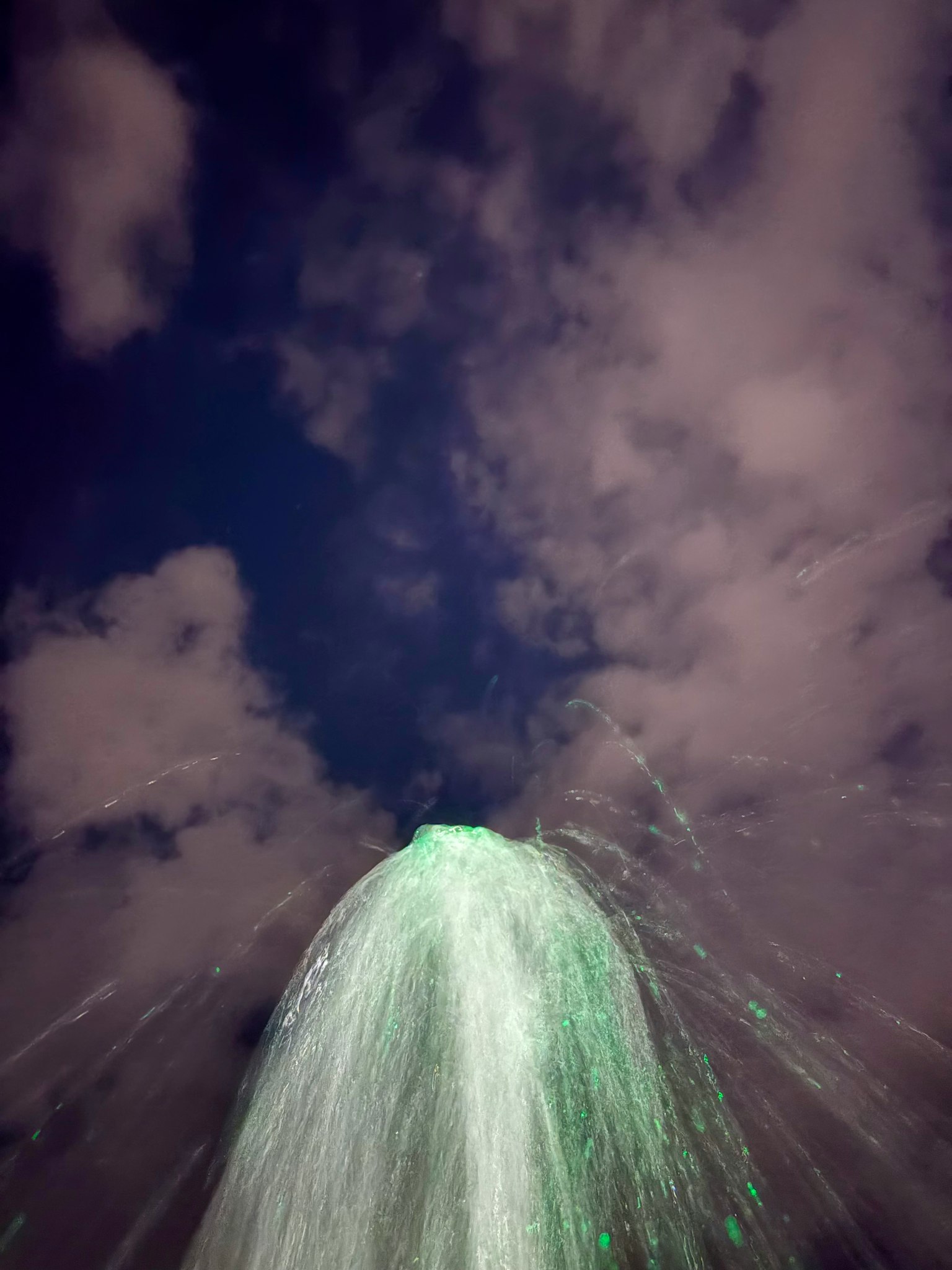 夜空に向かって噴き上がる緑色の噴水の水流