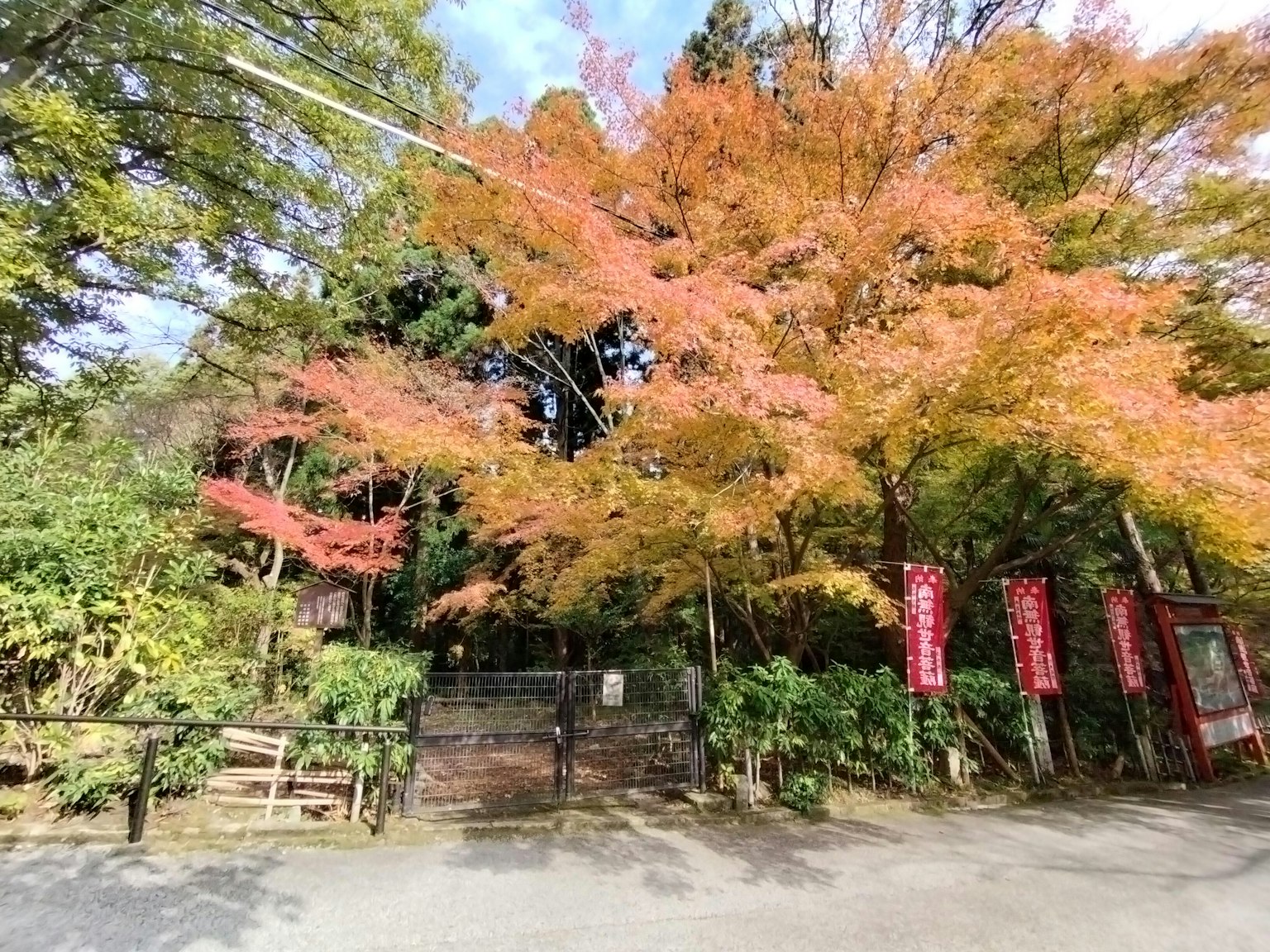 Entrance to a garden with beautiful autumn foliage green plants and red banners