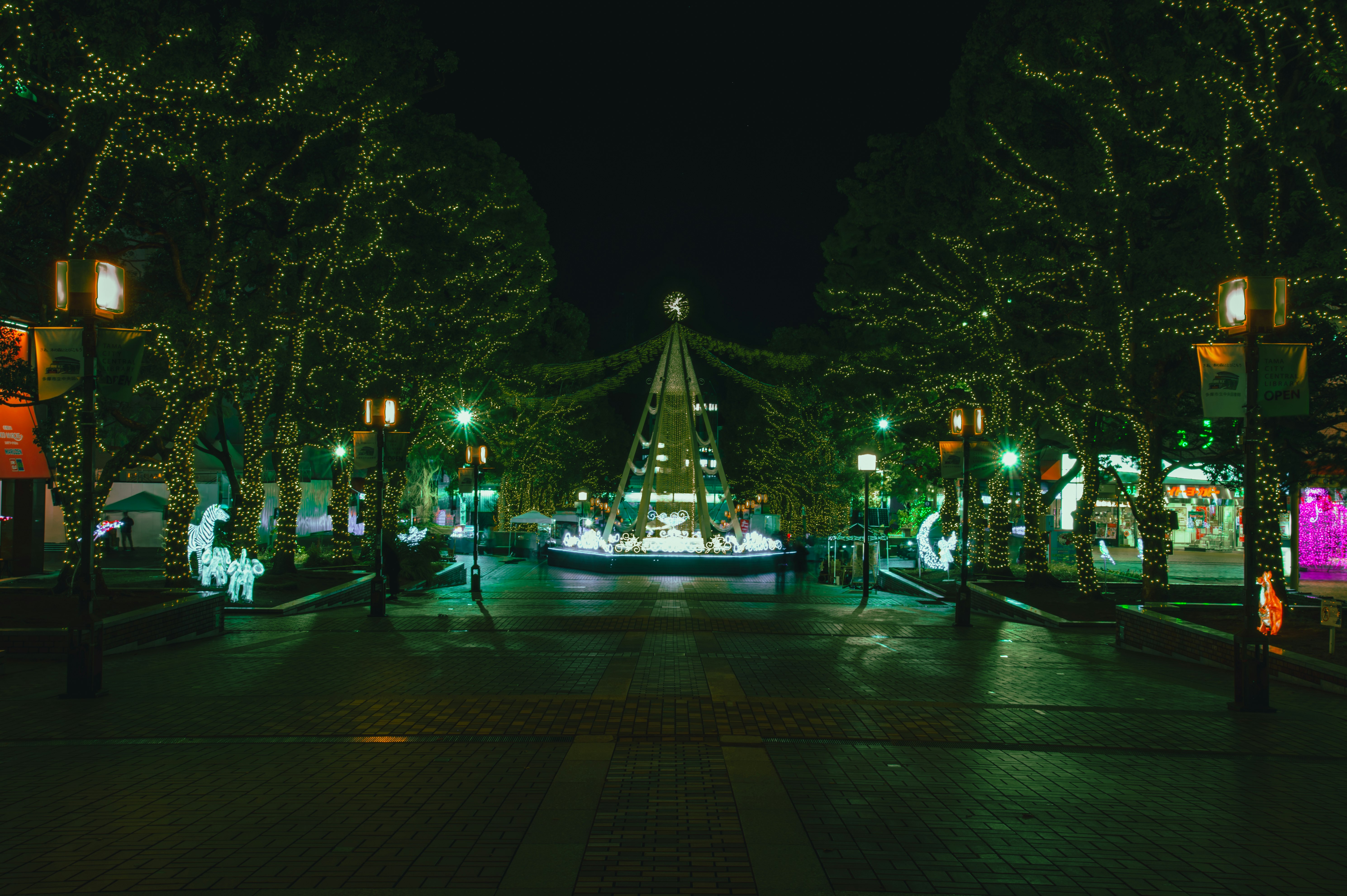 夜の公園でライトアップされたモニュメントと並木の遊歩道