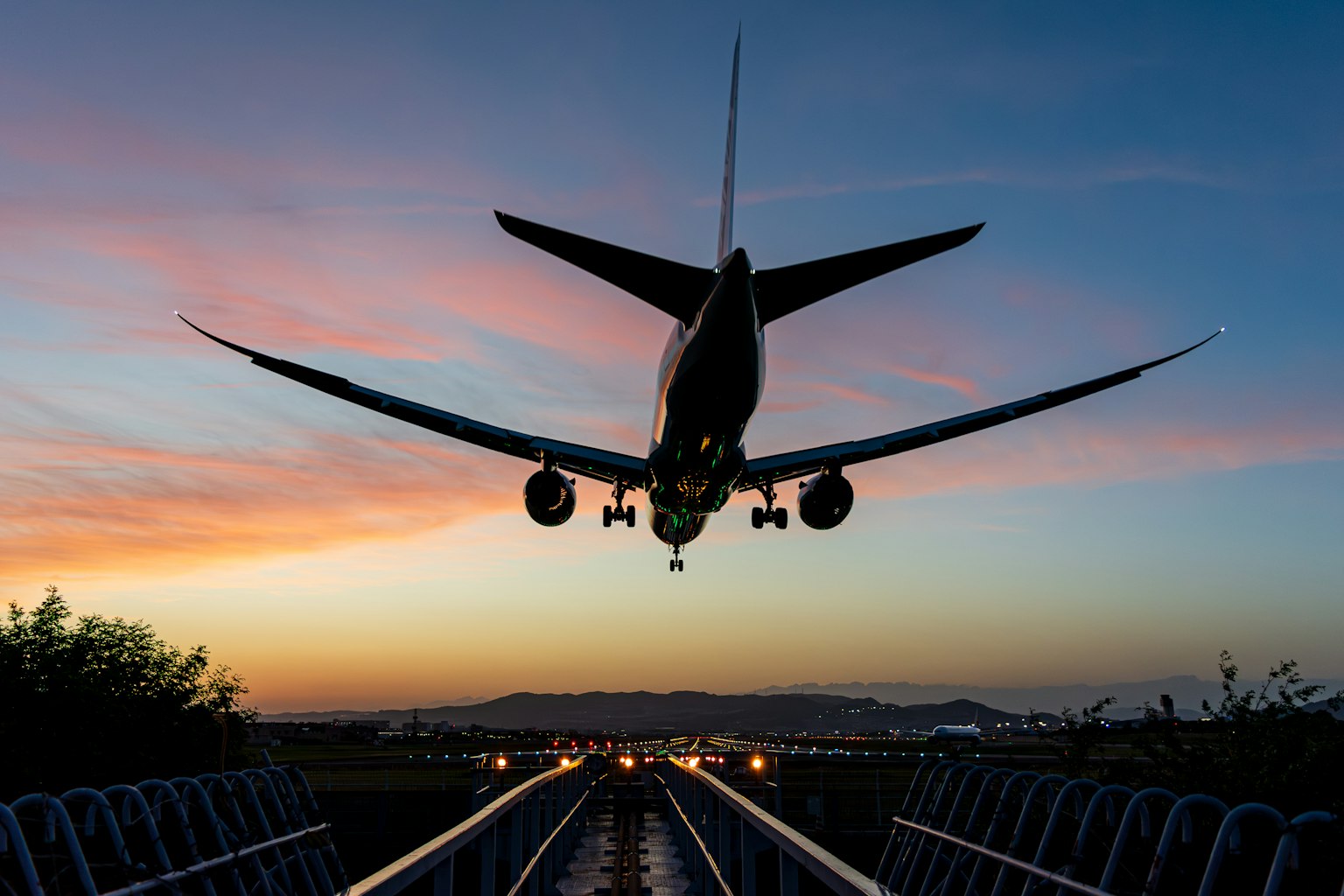 夕焼けの空を背景に着陸する航空機のシルエット