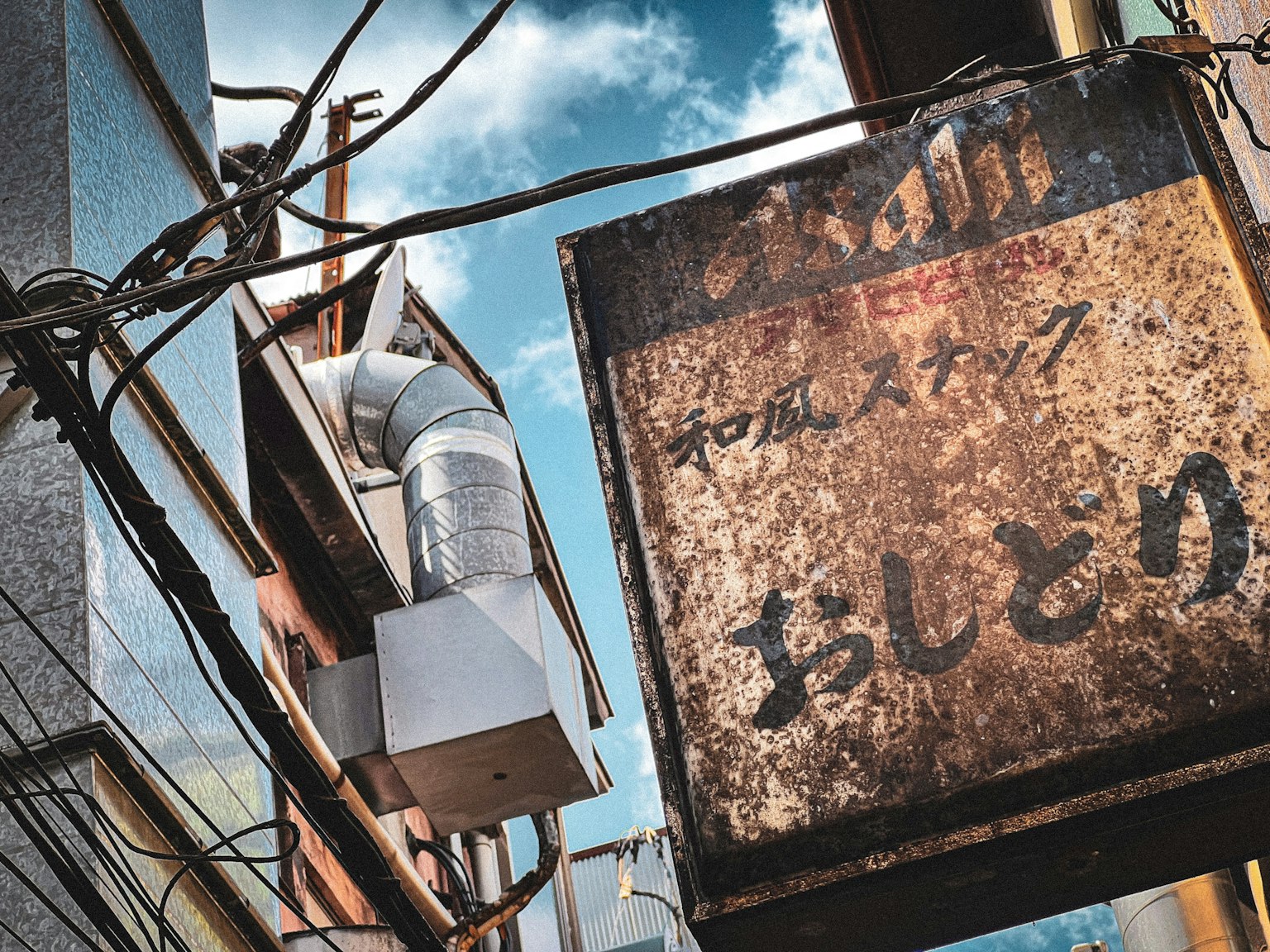 Narrow alley scene featuring an old sign and visible piping