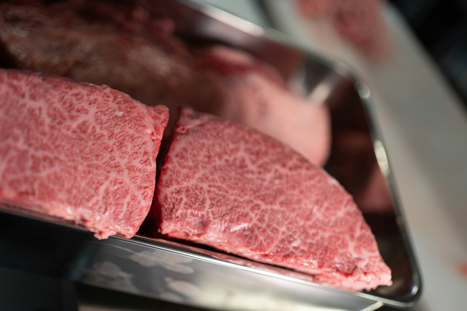 Belle fette di carne marmorizzata disposte su un vassoio di metallo