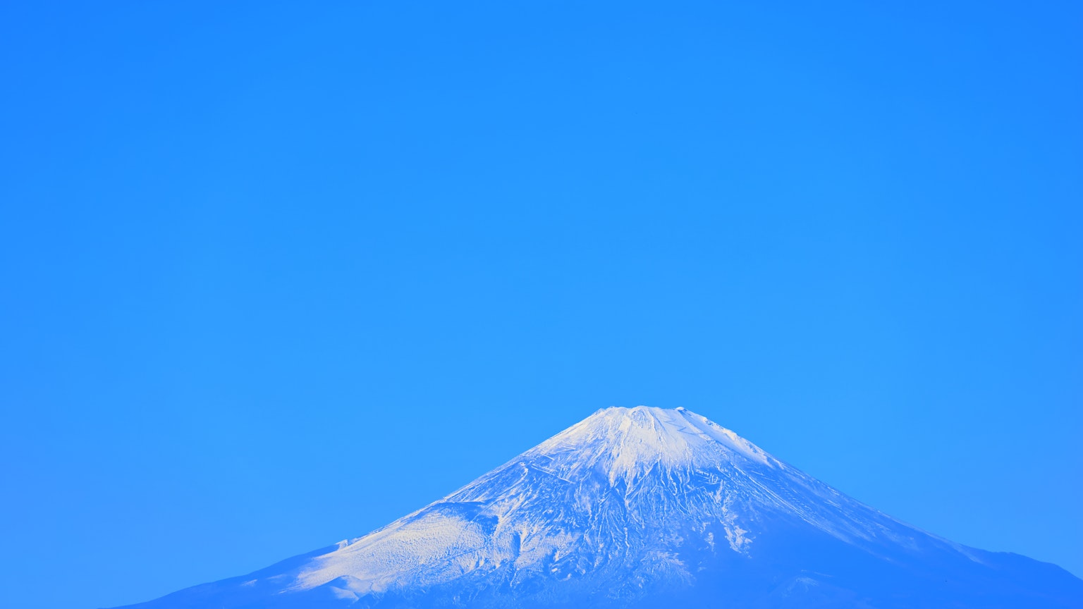 Sommet enneigé du mont Fuji contre un ciel bleu clair