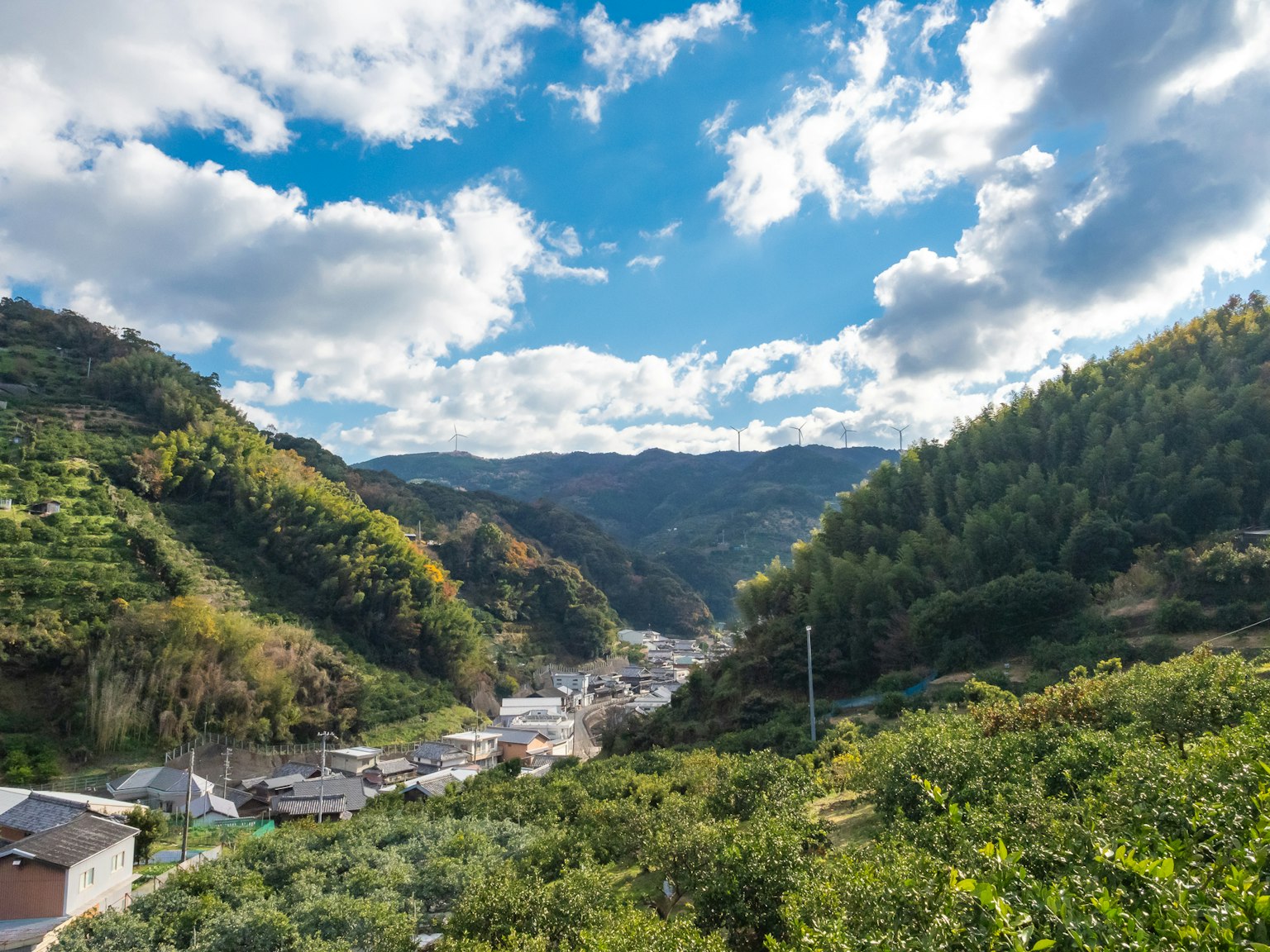 Vue panoramique de montagnes verdoyantes et d'un ciel bleu avec des maisons de village visibles