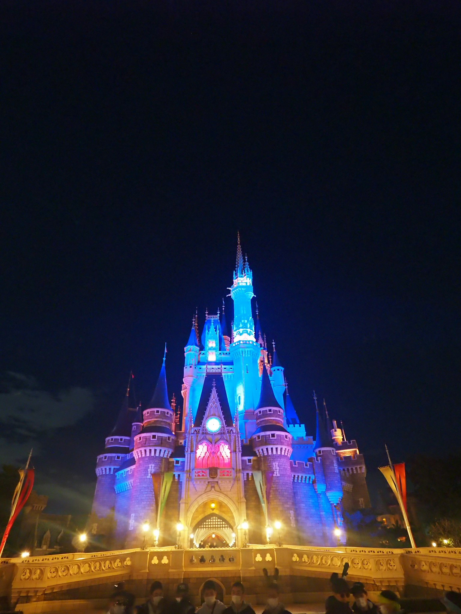 Castillo de Disney iluminado por la noche con luces azules y moradas