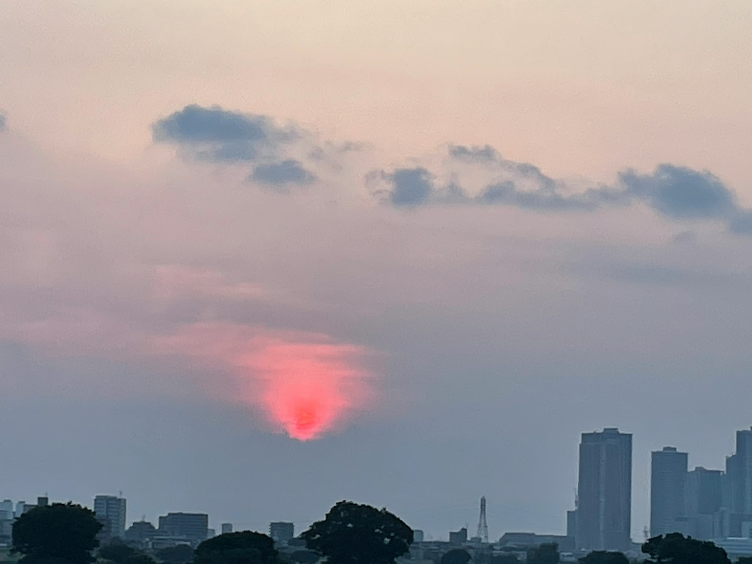 Stadtansicht mit einem teilweise hinter Wolken sichtbaren Sonnenuntergang