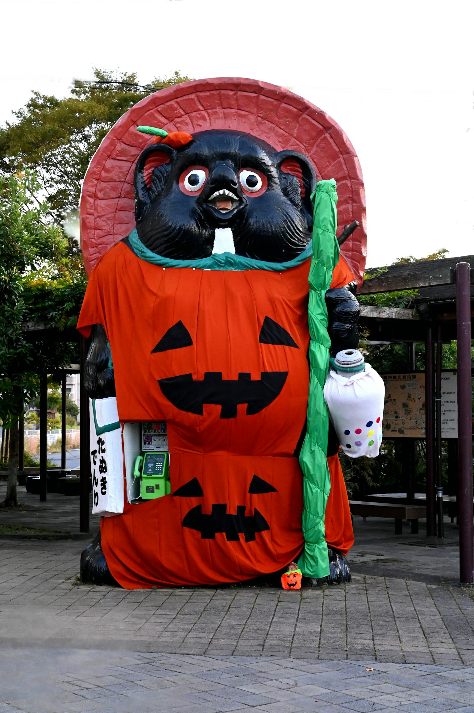 Patung tanuki besar berpakaian kostum Halloween dengan desain labu