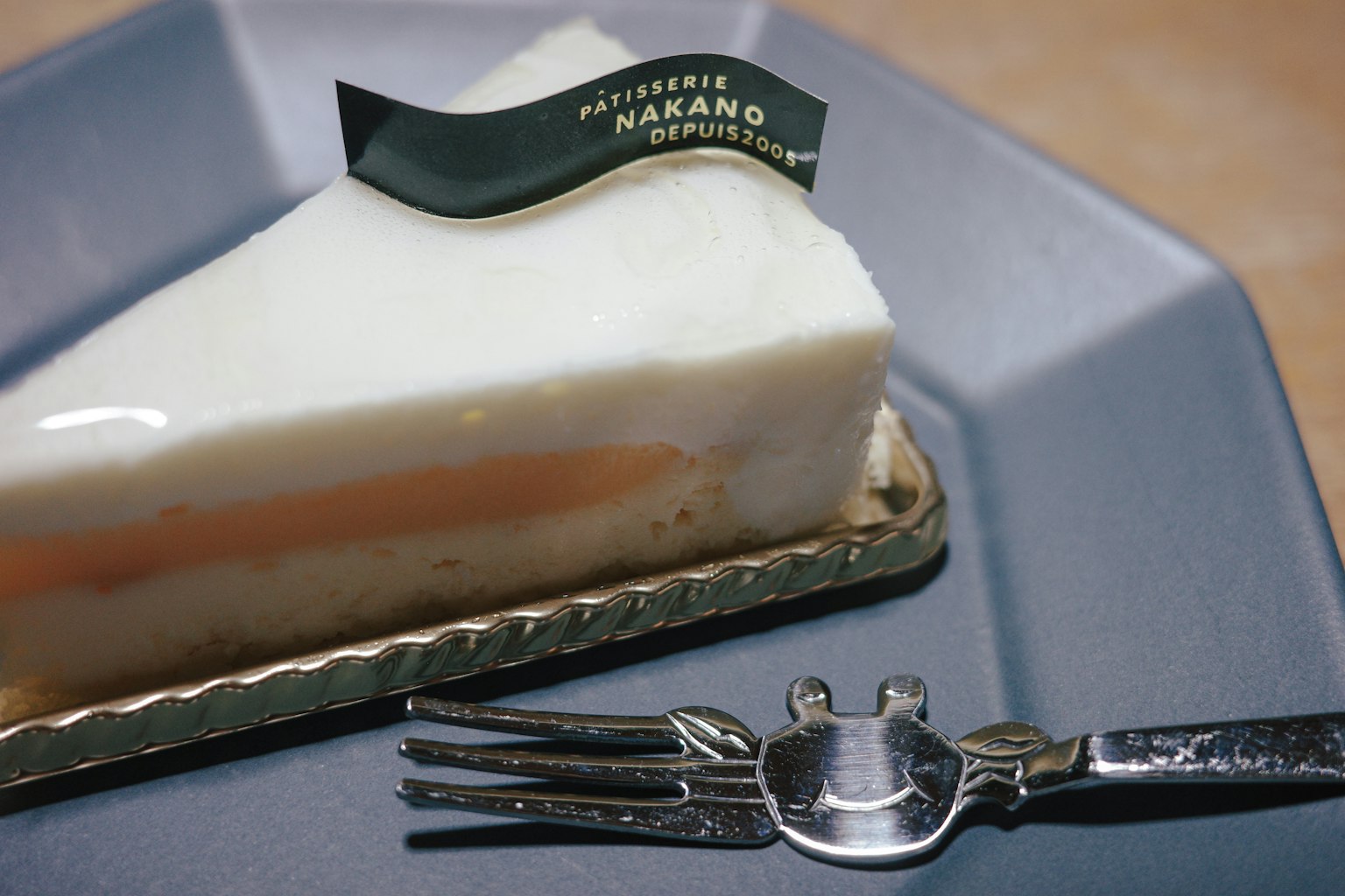 Slice of white cake with orange layer and green logo topper