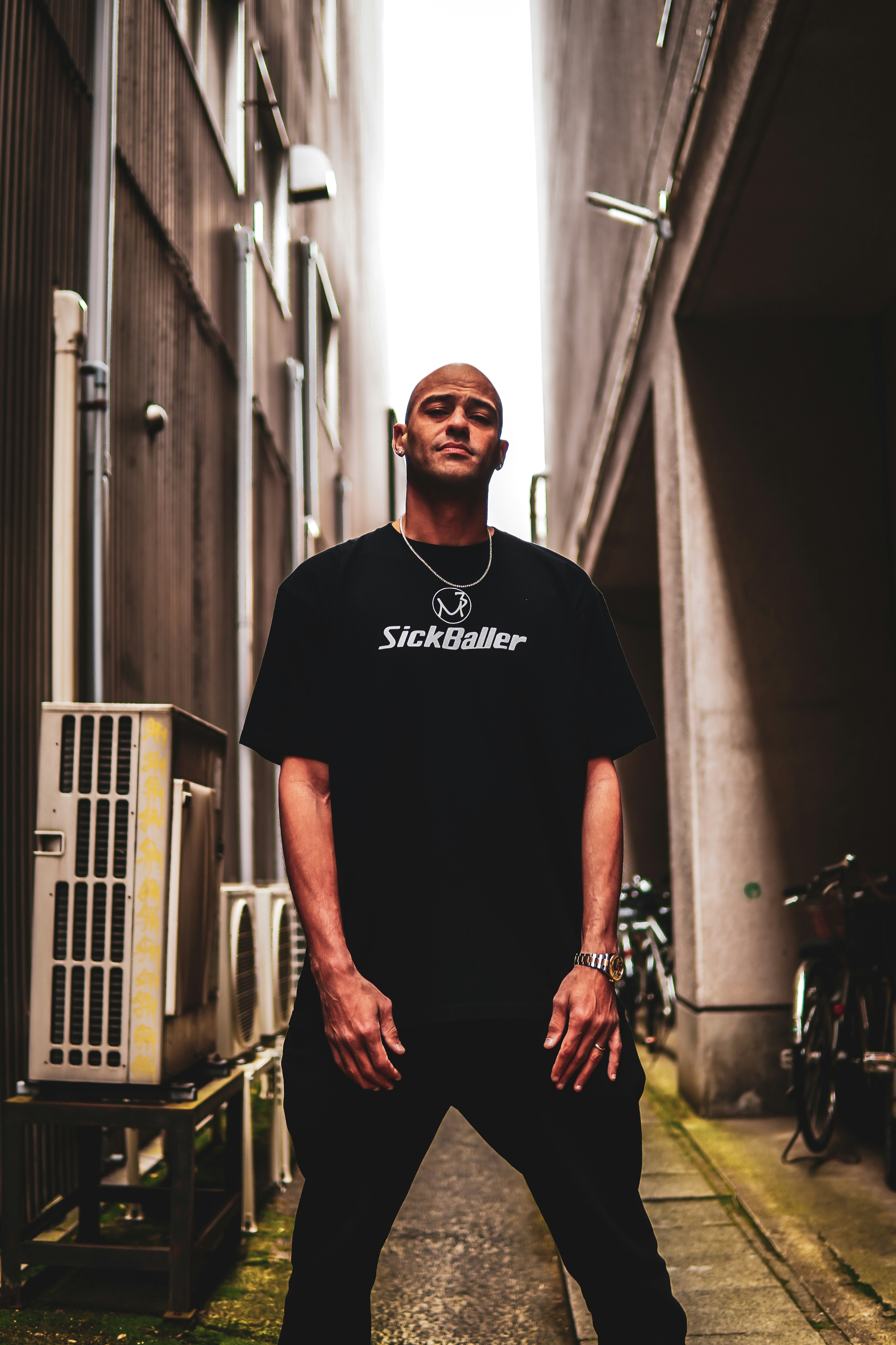 路地の奥に立つ黒Tシャツの男性