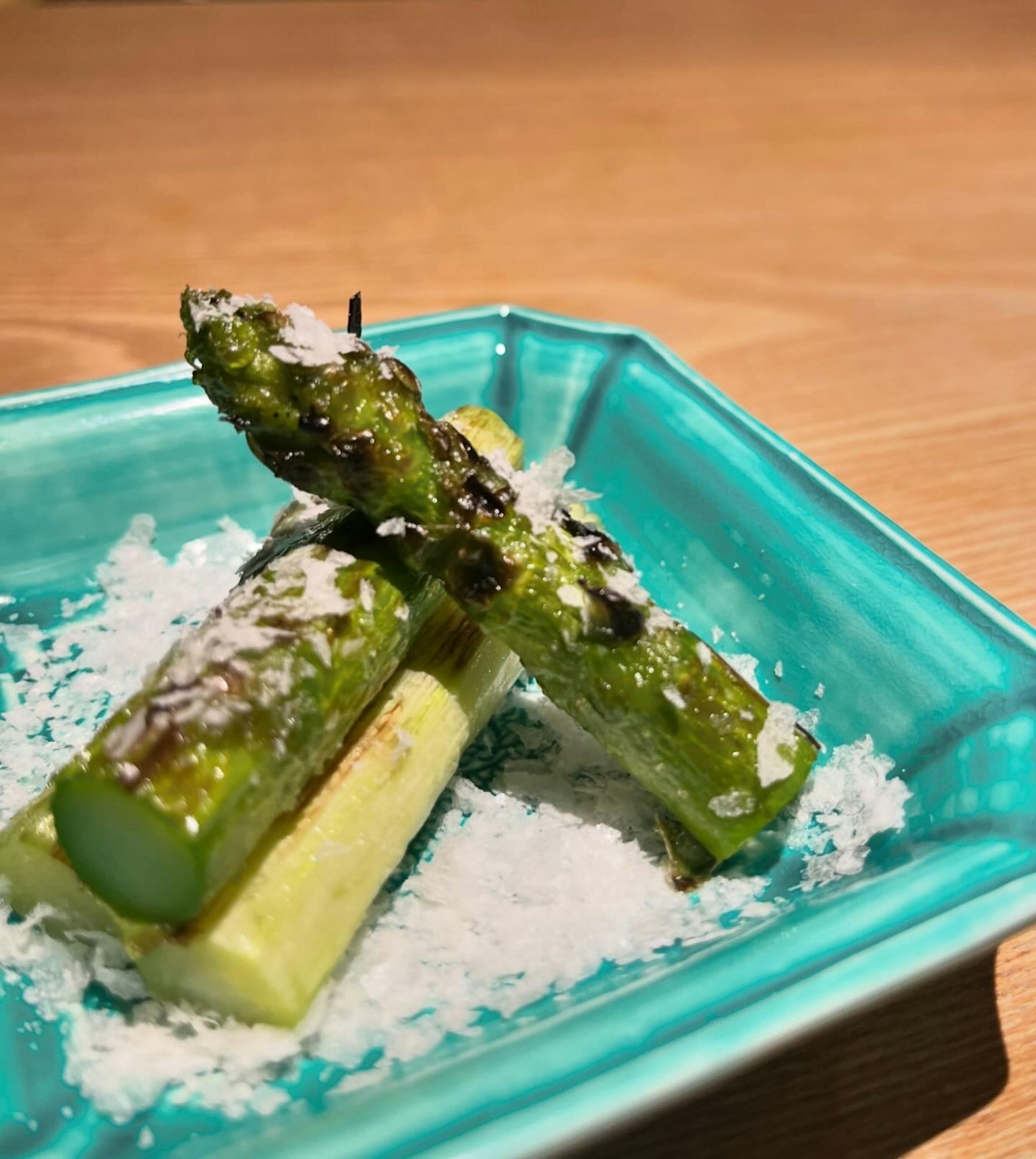 Gegrillte Spargel mit Kokosflocken auf einem türkisfarbenen Teller